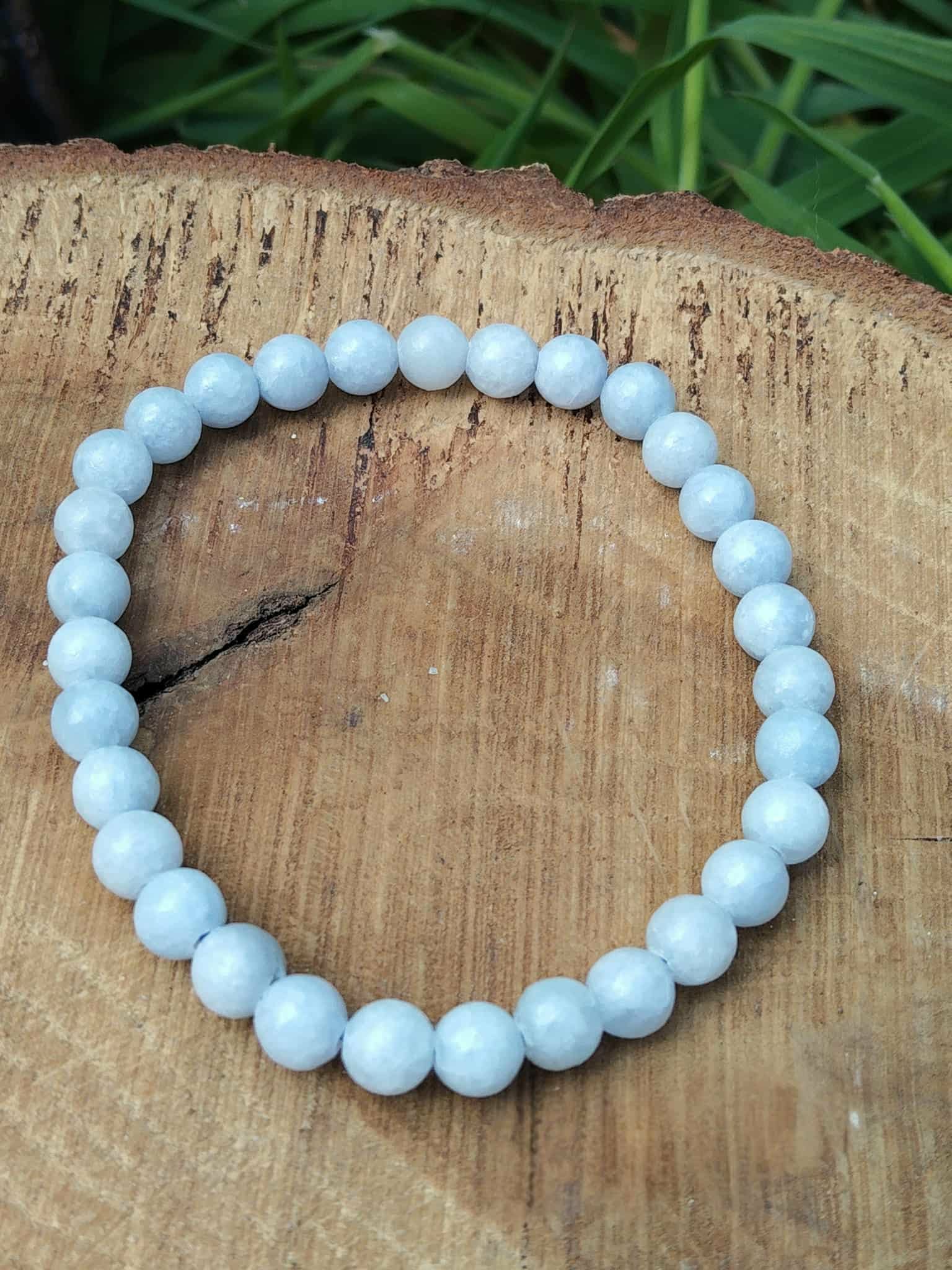 Bracelet en célestine 6 mm sur rondin de bois avec feuillage vert, perles bleu pastel, légèreté émotionnelle, clarté douce et bien-être serein