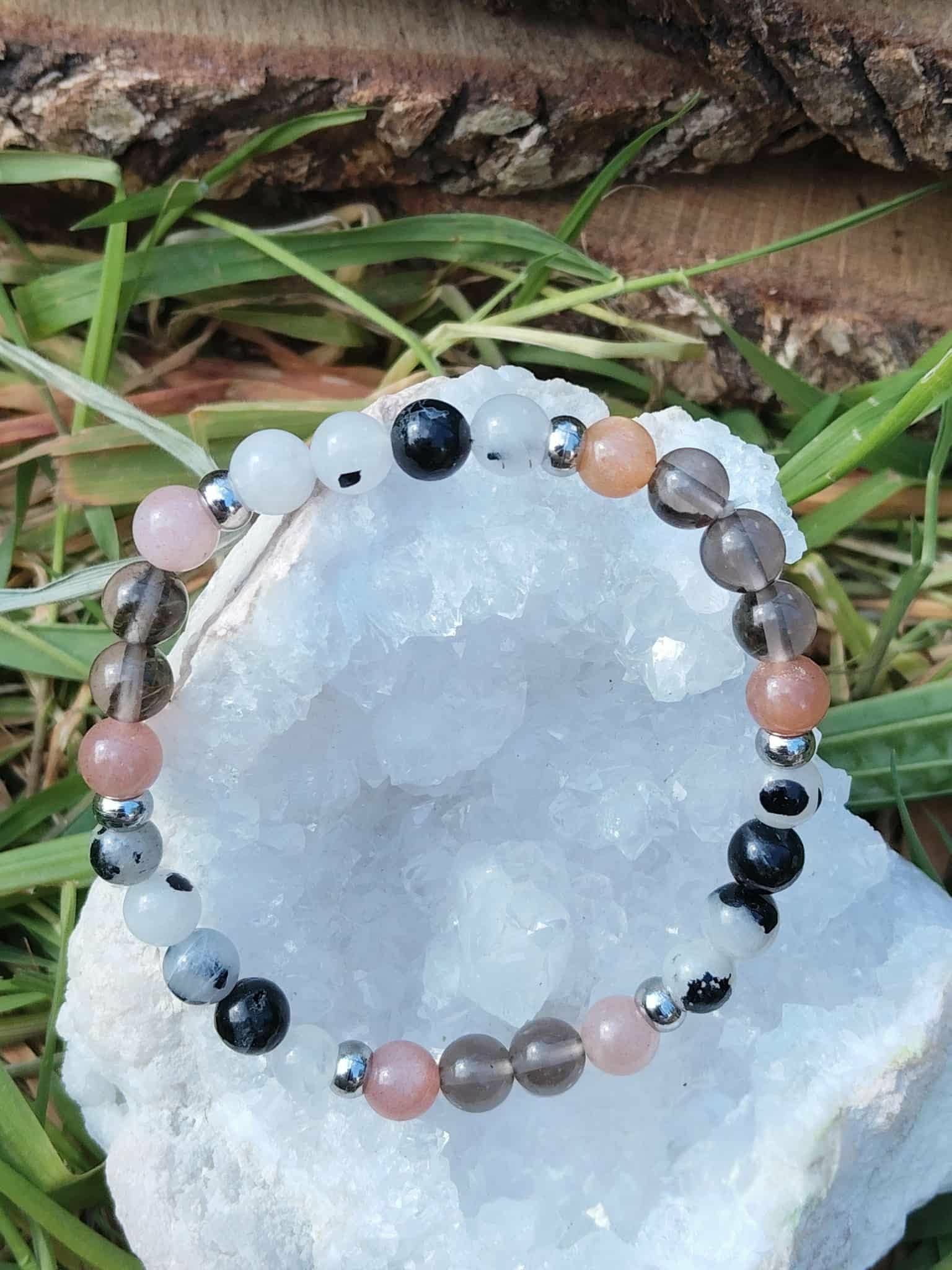Bracelet Deuil photographié sur amas de quartz avec feuillage vert, bijou en pierre naturelle pour accompagner les transitions et soutenir l’équilibre émotionnel