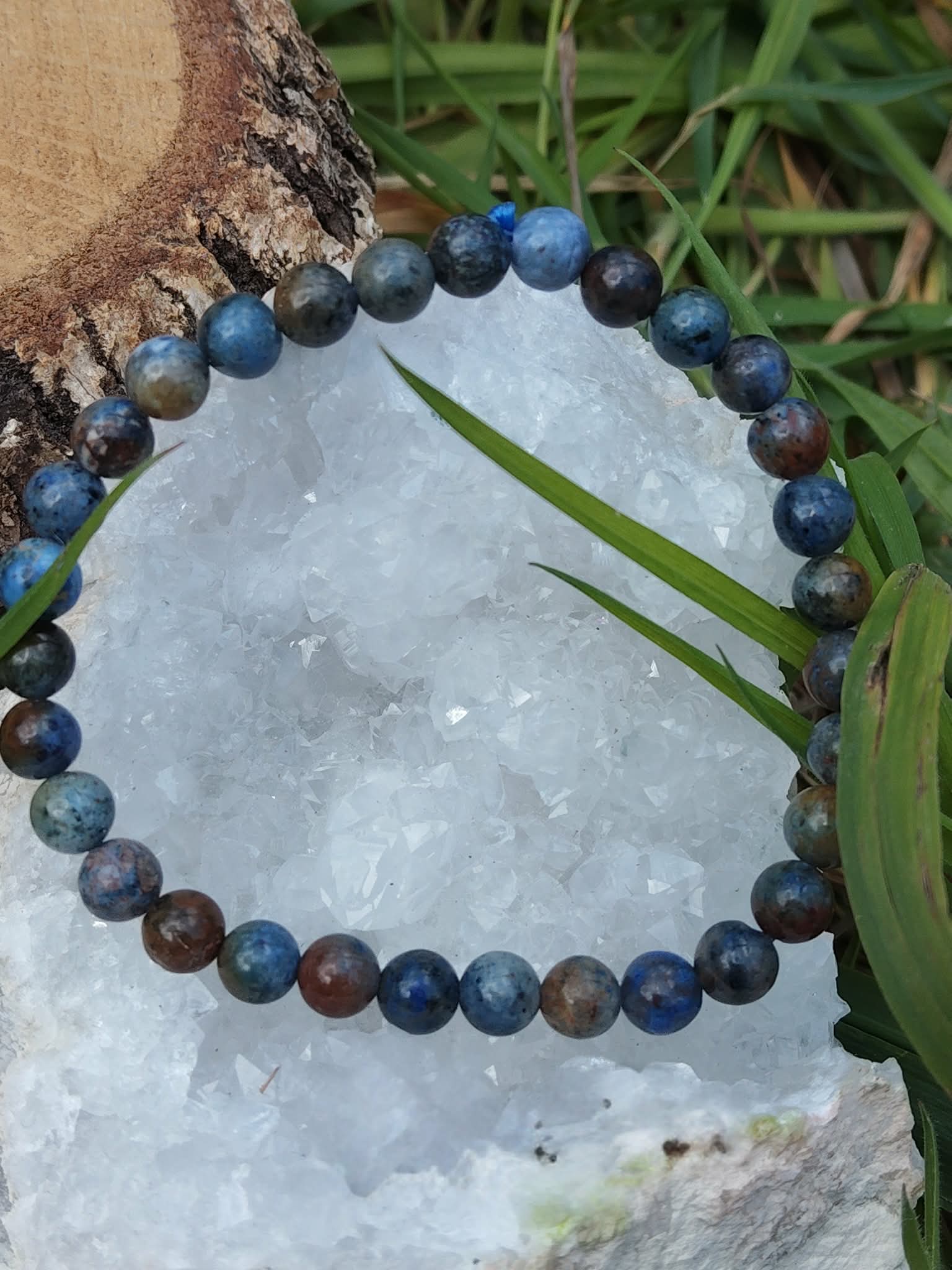 Bracelet dumortiérite 6 mm sur pierre claire avec brin d’herbe et feuillage vert, centrage, réflexion nette et attention plus stable