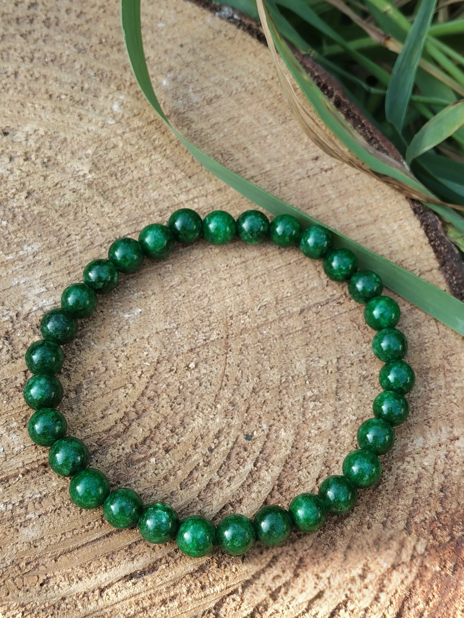 Bracelet jade africain 6 mm sur décor boisé et végétal, perles vert forêt et vert jade pour lâcher-prise et harmonie émotionnelle