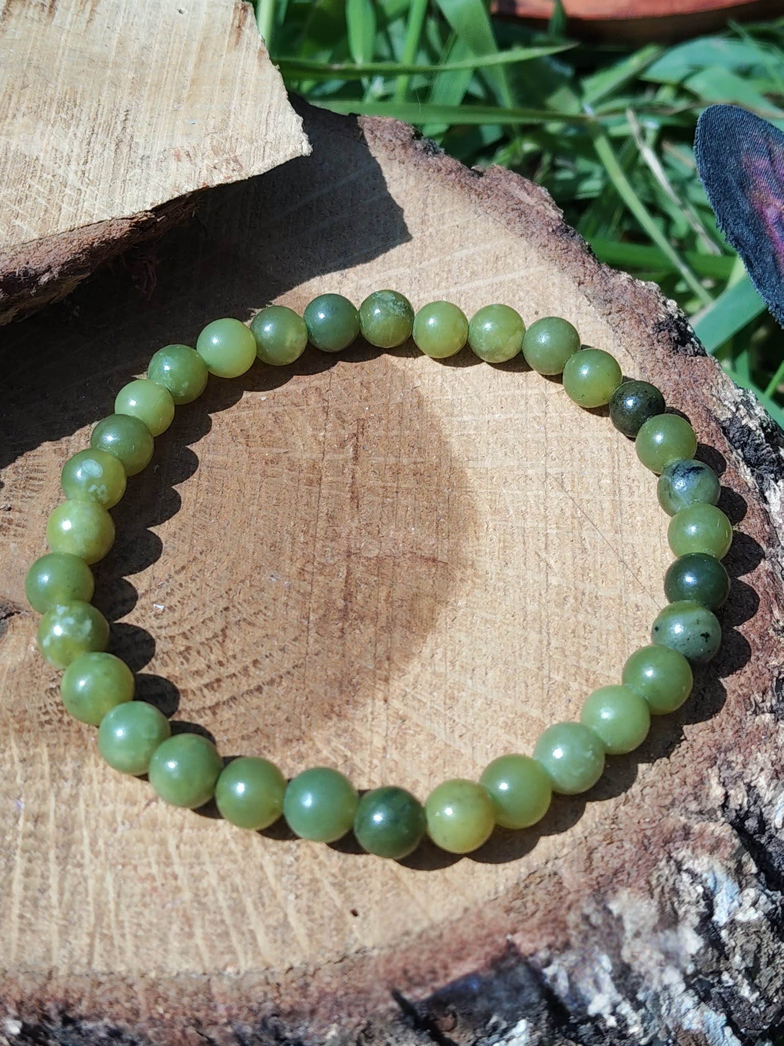 Bracelet jade du Canada 6 mm sur rondin de bois avec écorce et feuillage, perles vert clair, vert olive et vert mousse pour stabilité douce et sagesse intérieure