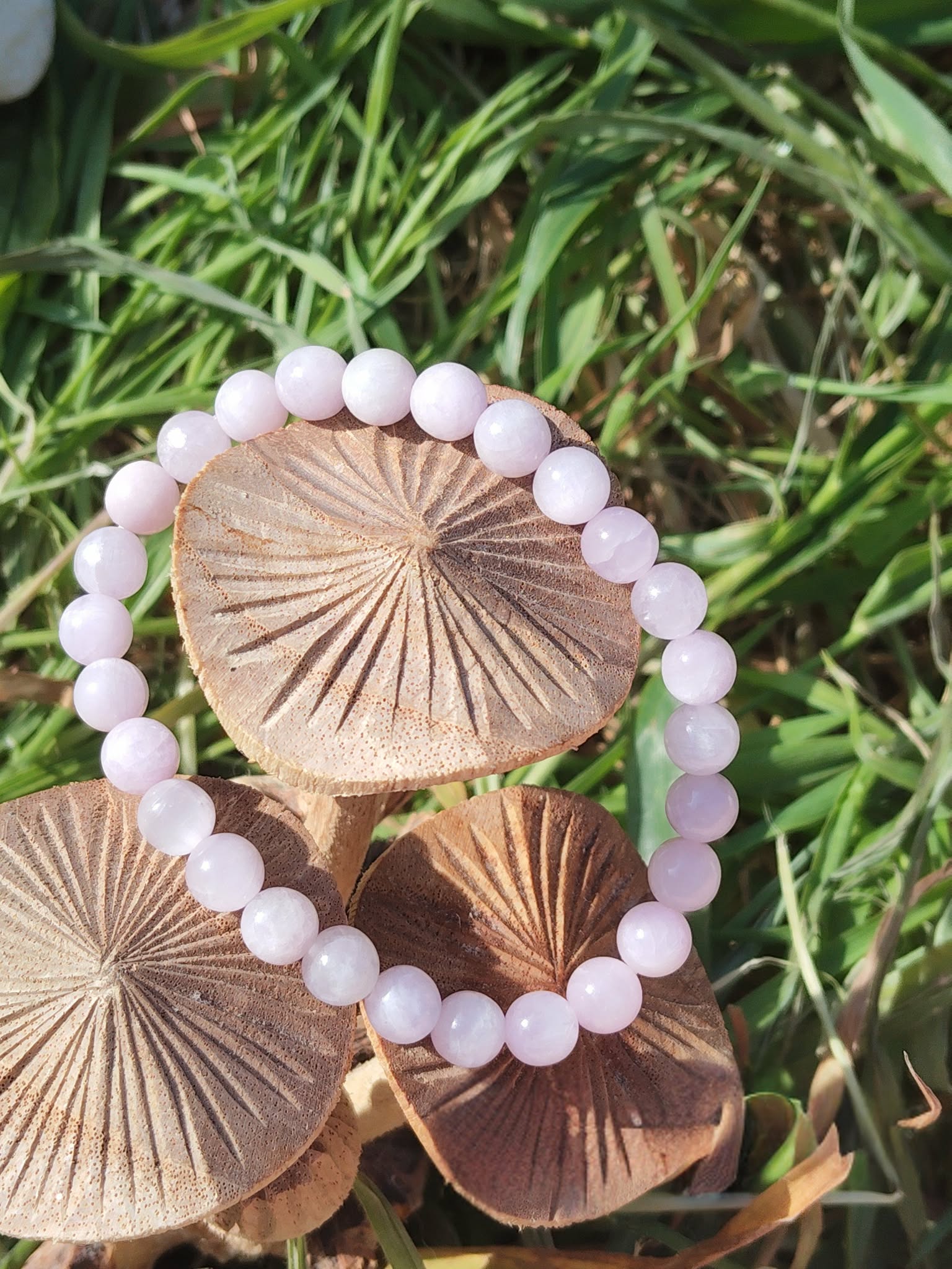 Bracelet kunzite 6 mm sur champignons en bois et herbe verte, perles rose lilas et nuances translucides, bienveillance, lâcher-prise et respiration intérieure