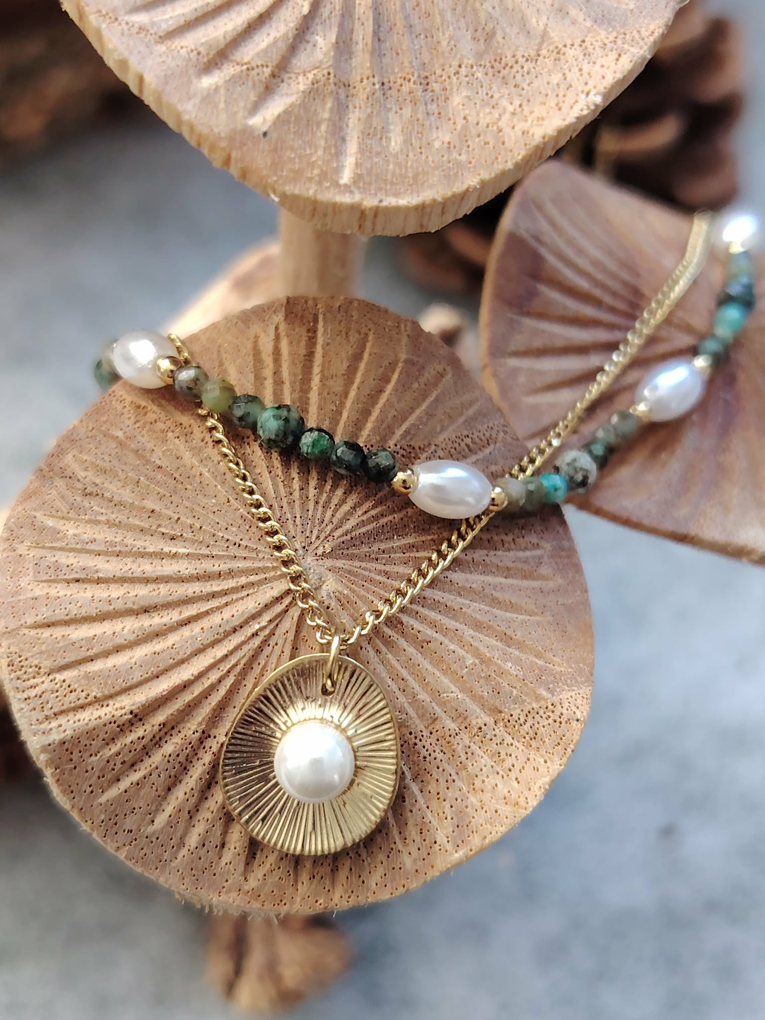 Collier double chaîne dorée acier inoxydable, perles blanches, pierres vertes, médaillon nacré, sur champignonsde bois.