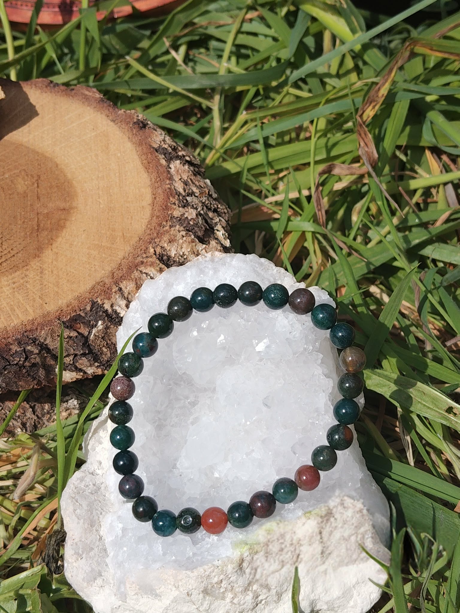 Bracelet jaspe héliotrope 6 mm sur amas de quartz, herbes en fond ; recentrage, stabilité, sérénité.