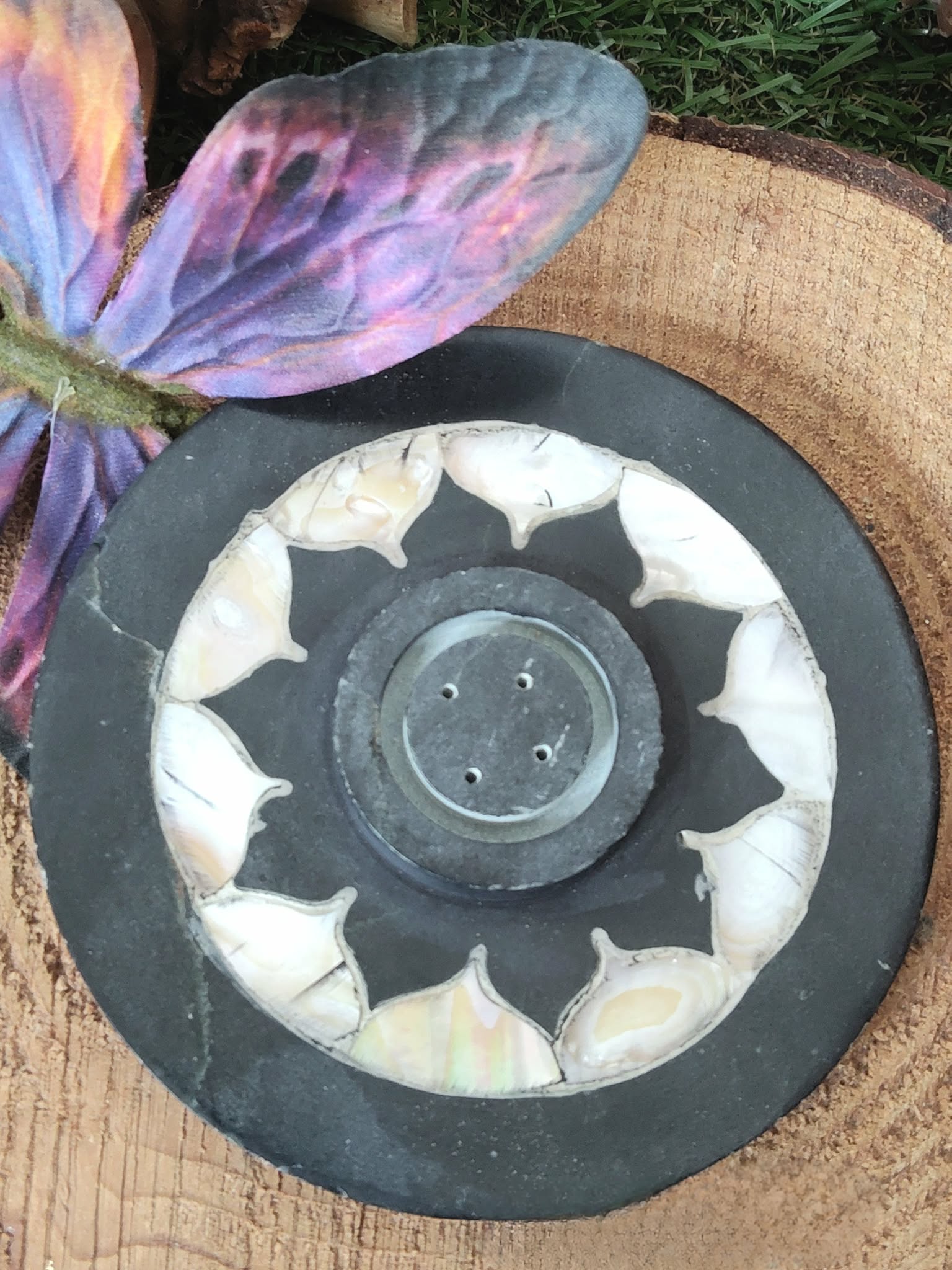 Porte-encens lotus en pierre ollaire noir et blanc, motif fleur au centre, posé sur support en bois avec fleurs en décor, ambiance zen, aide à la détente, au recentrage et à apaiser l’esprit.