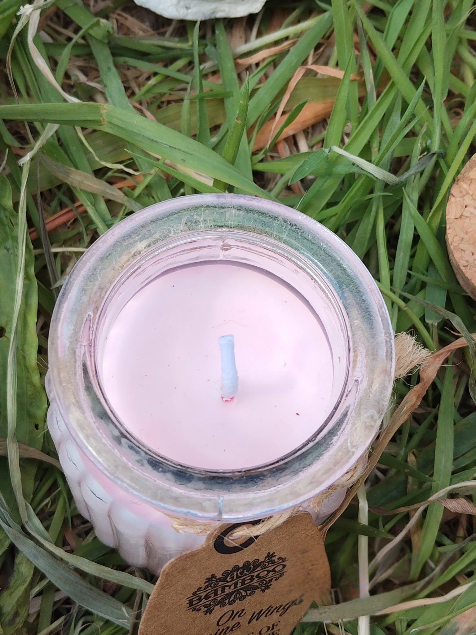 Vue du dessus bougie jasmin en cire de soja, cire blanche et mèche centrée, pot verre dans l’herbe, calme, clarté, apaisement.