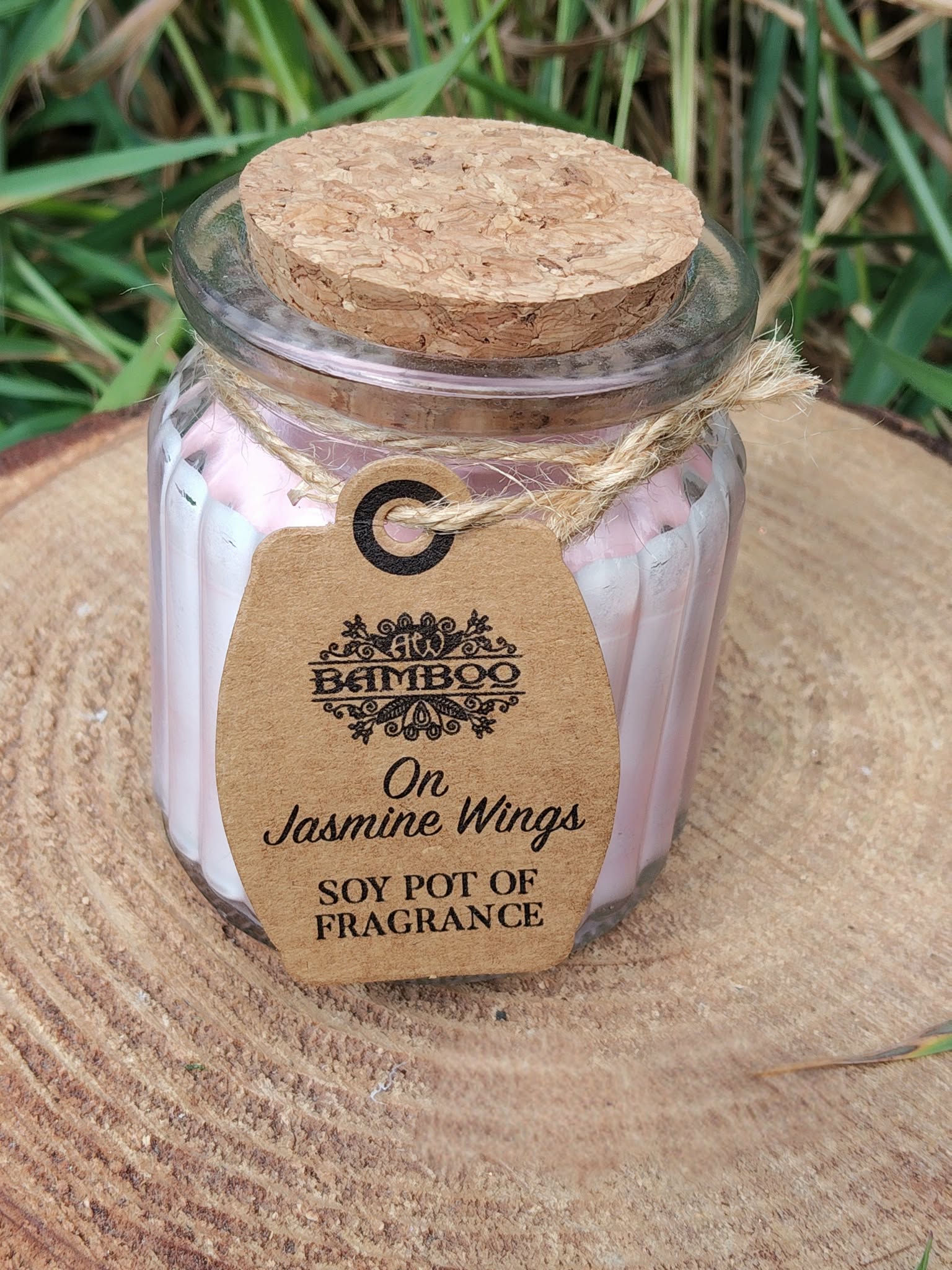 Bougie parfumée jasmin en cire de soja, pot en verre avec couvercle liège, sur tranche de bois avec herbes, douceur, apaisement, sérénité, cocooning.