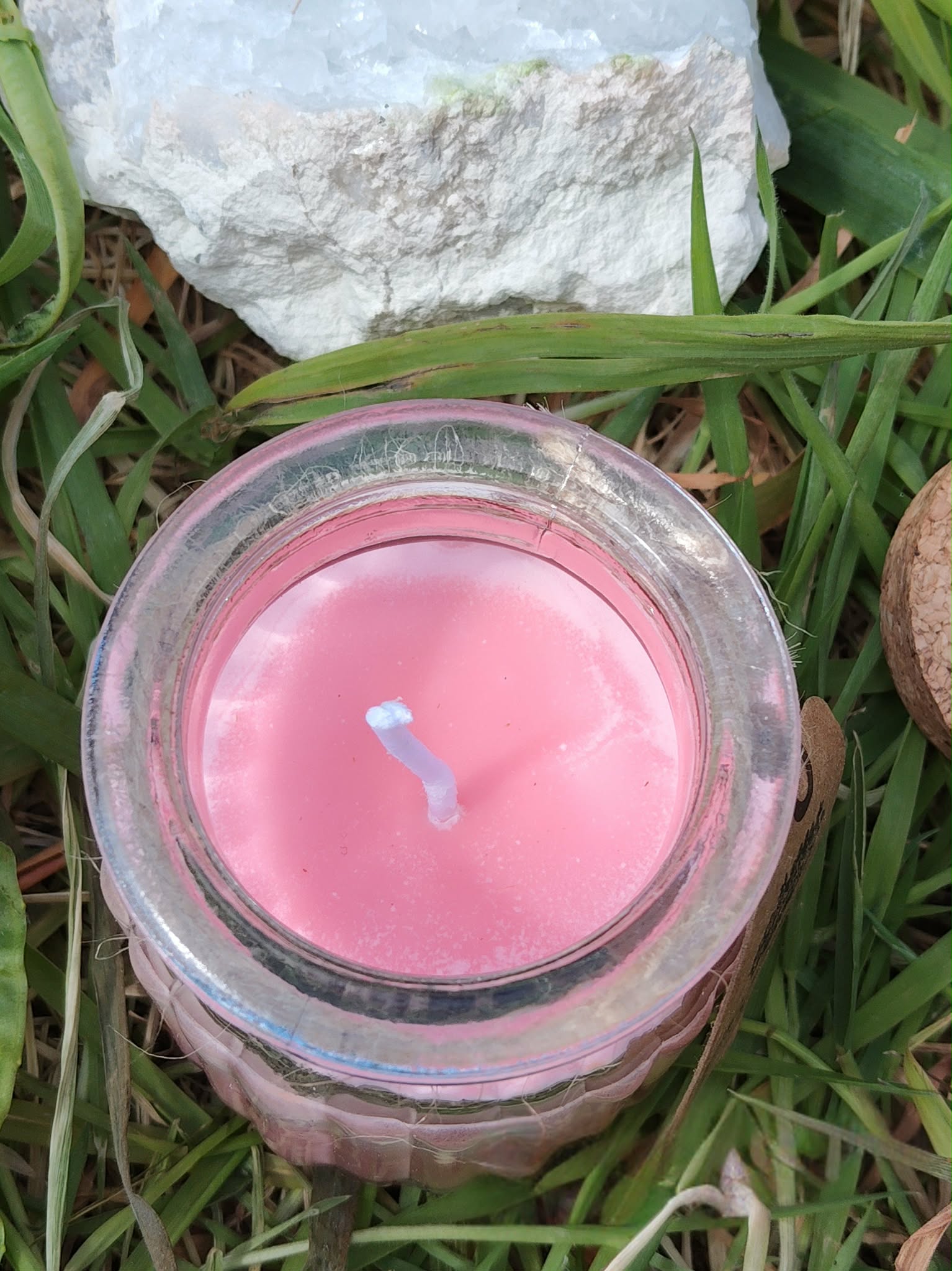Vue du dessus bougie Rose de Minuit en cire de soja, cire rose et mèche centrée, pot verre dans l’herbe, douceur, calme, apaisement.