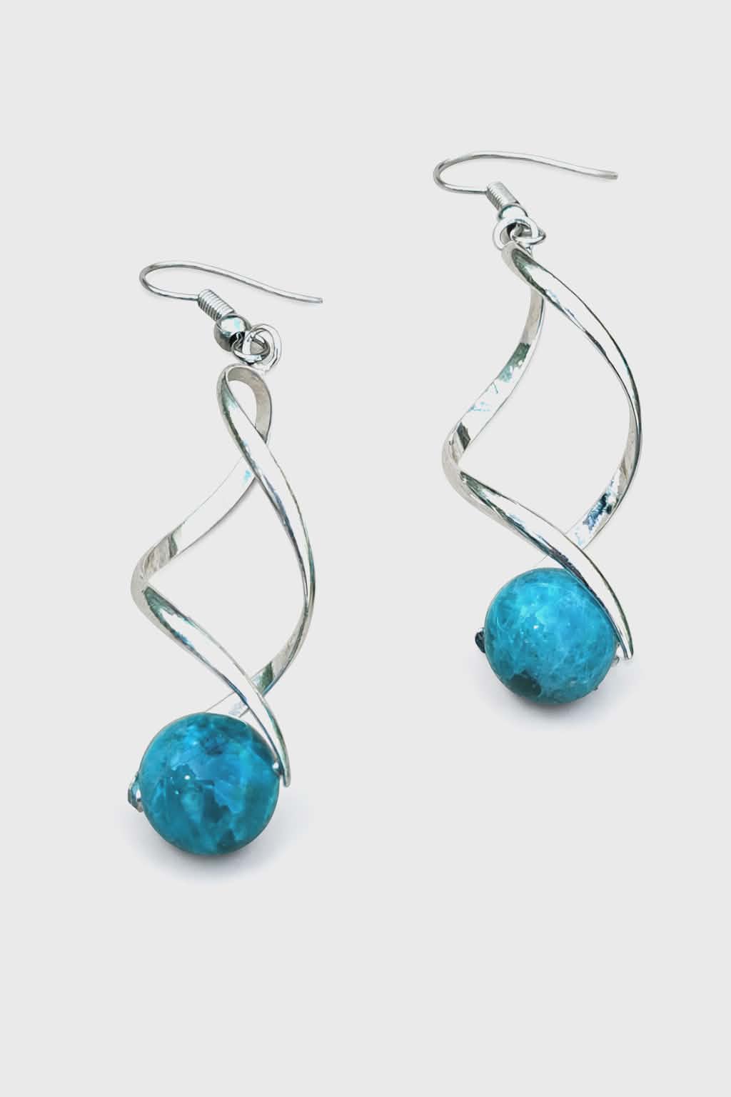 Boucles d’oreilles spirales argentées avec perles d’apatite bleue sur fond blanc, clarté, motivation, communication.