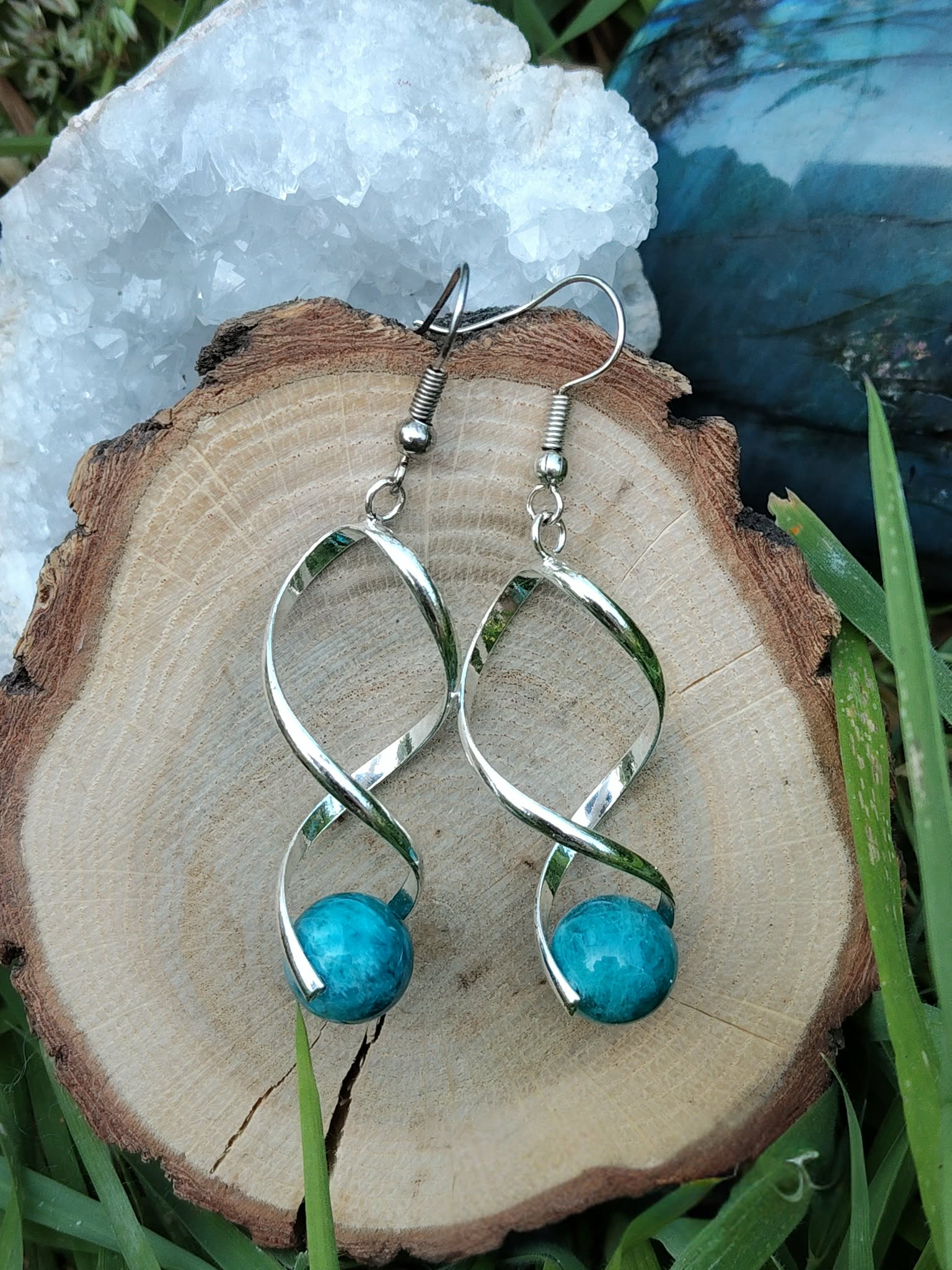 Boucles d’oreilles spirales argentées avec perles d’apatite bleue sur rondin de bois, géode et brins de mousse, clarté, motivation, expression.