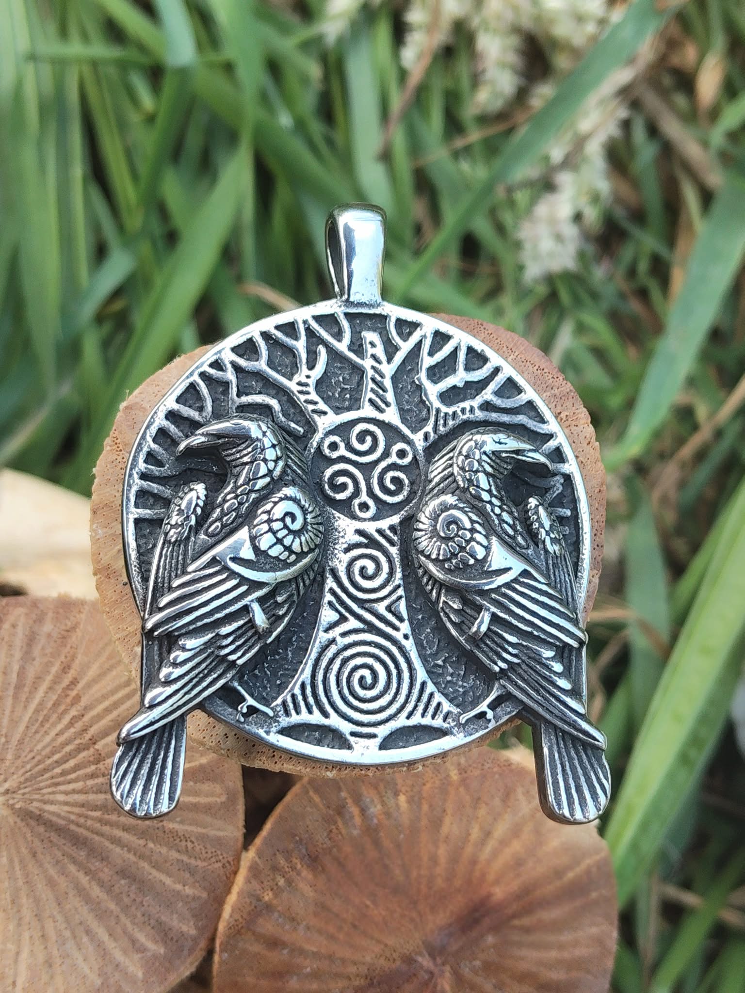 Pendentif viking double corbeaux avec triskèle posé sur champignons décoratifs en bois, métal argenté et décor végétal pour style nordique affirmé