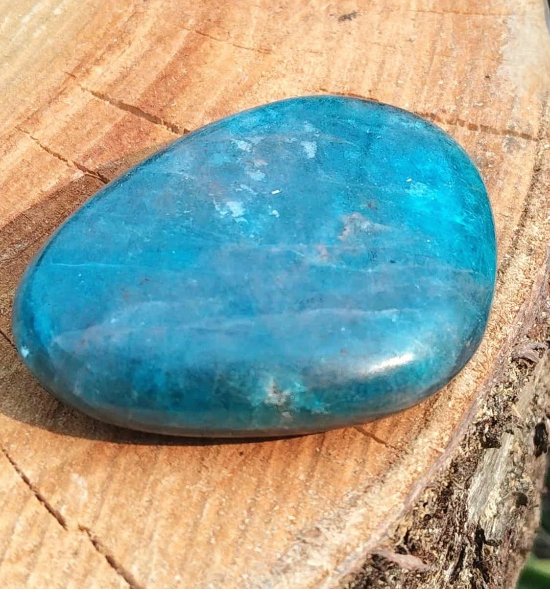 Galet d’apatite bleue poli posé sur décor nature, pierre naturelle évoquant la tranquillité, l’inspiration et la justesse intérieure.