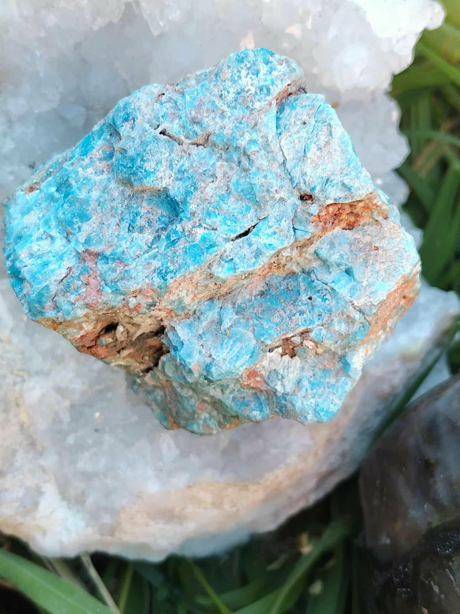 Apatite bleue brute sur fond blanc, éclats turquoise et veines ocre, pierre naturelle évoquant l’élan créatif, la présence à soi et la fluidité d’expression.