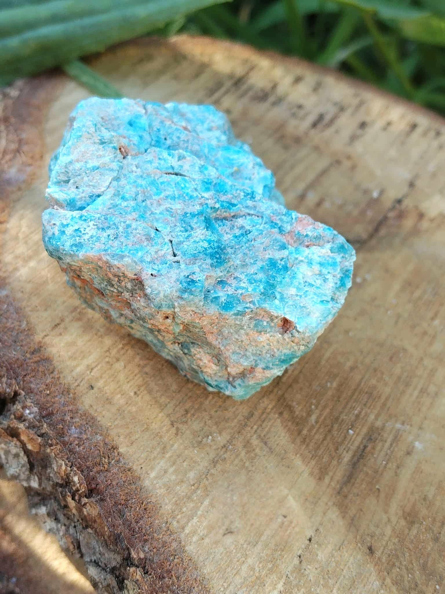 Apatite bleue brute bleu lagon avec matrice claire sur fond blanc, pierre naturelle reliée à la créativité, à l’assurance et à la clarté intérieure.