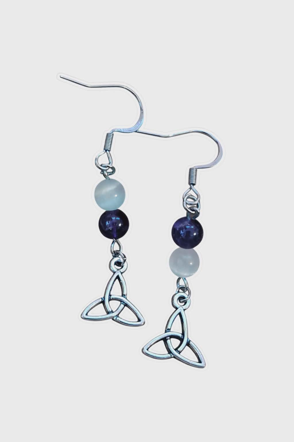 Boucles d’oreilles pendantes triquetra argenté création Magic Gaïa, perles améthyste et sélénite, style ésotérique, fond blanc – apaisement, clarté mentale, intuition.