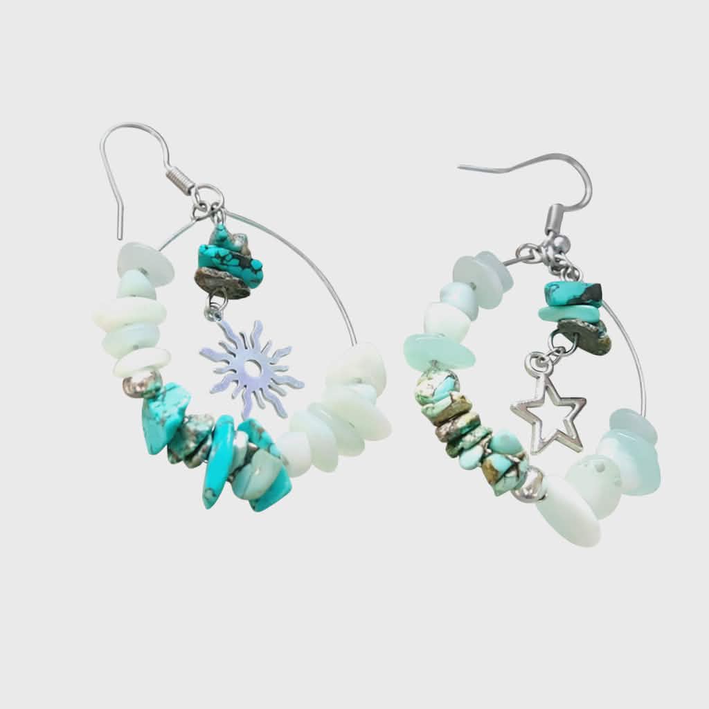 Boucles d’oreilles Ombre &amp; Lumière création Magic Gaïa, anneaux argentés avec amazonite et éclats de turquoise, charms étoile et soleil, photo sur support clair texturé.