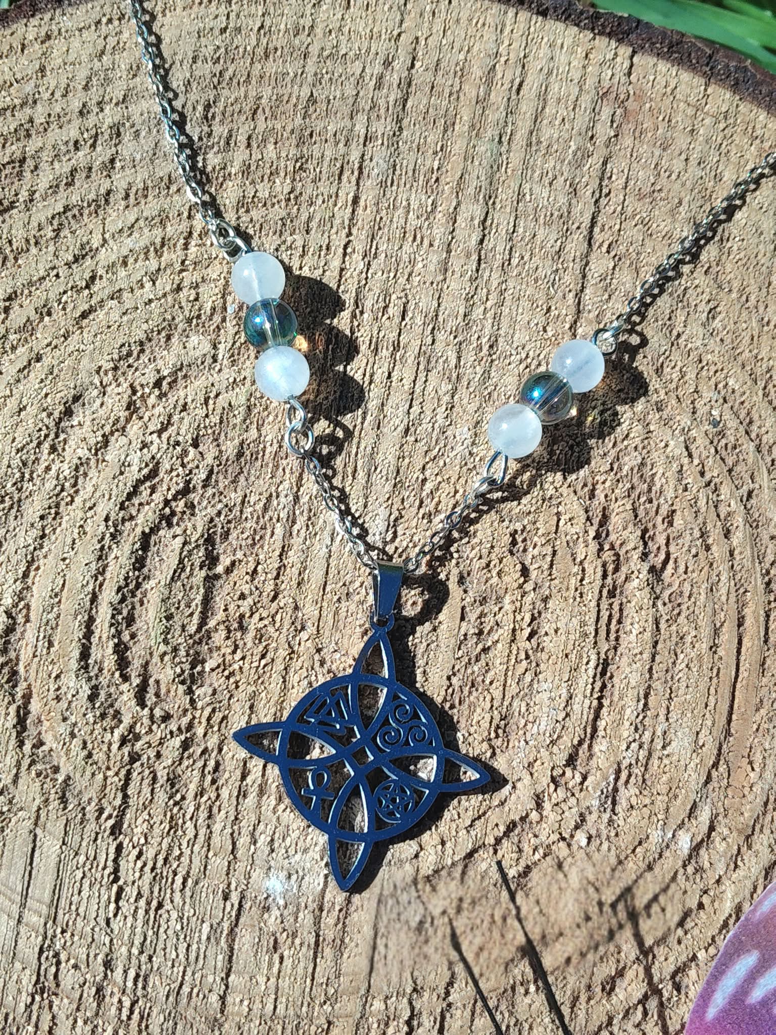 Pendentif nœud de sorcière sur chaîne acier inoxydable avec décor bois et éléments verts, perles iridescentes pour sensibilité douce et intuition claire