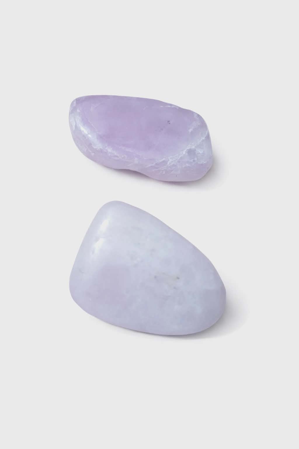 Pierre roulée de kunzite violette sur fond blanc, polie et translucide, galet naturel associé à la sérénité, à la sensibilité apaisée et à l’équilibre affectif.