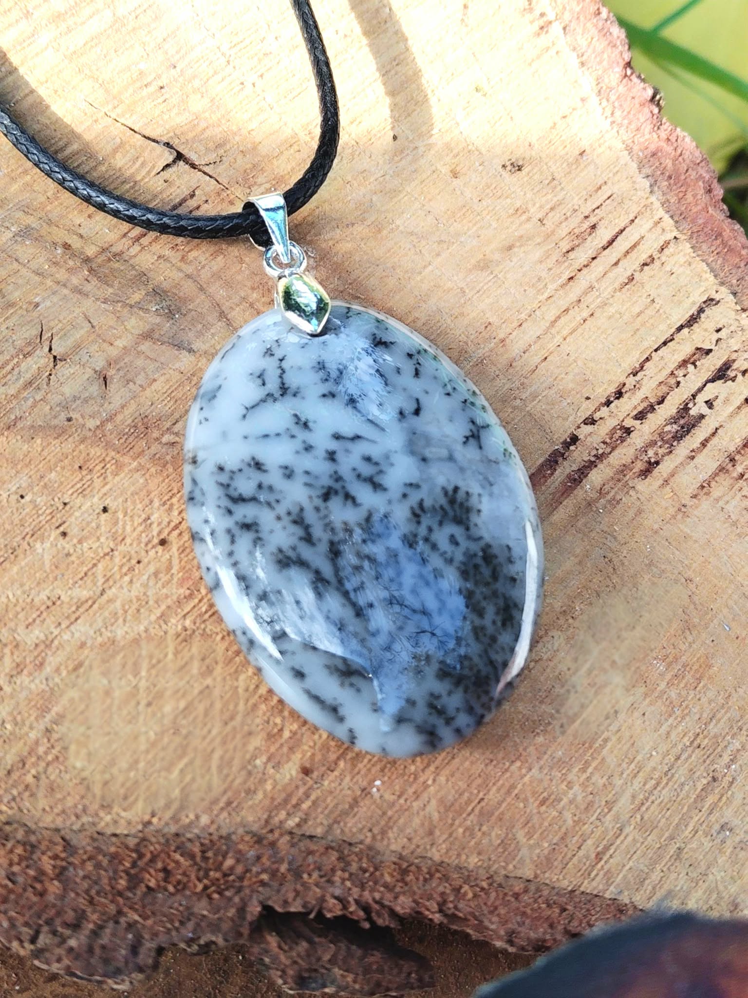Pendentif opale dendritique sur rondin de bois en extérieur, cordon noir et bélière argentée, sérénité mentale et sensation d’appui intérieur