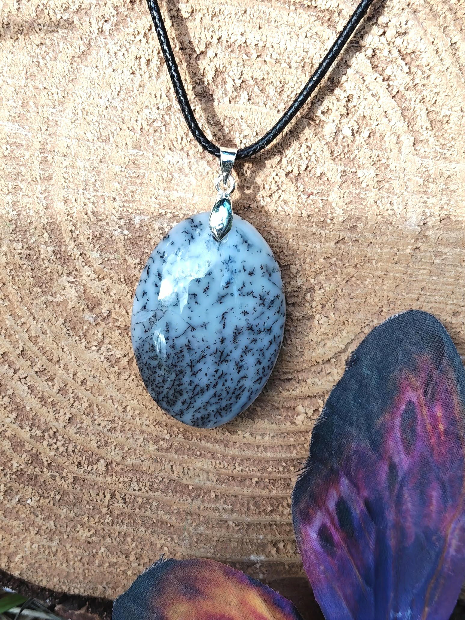 Pendentif opale dendritique ovale sur bois avec galet violet, cordon noir et bélière argentée, protection symbolique et ressenti plus apaisé
