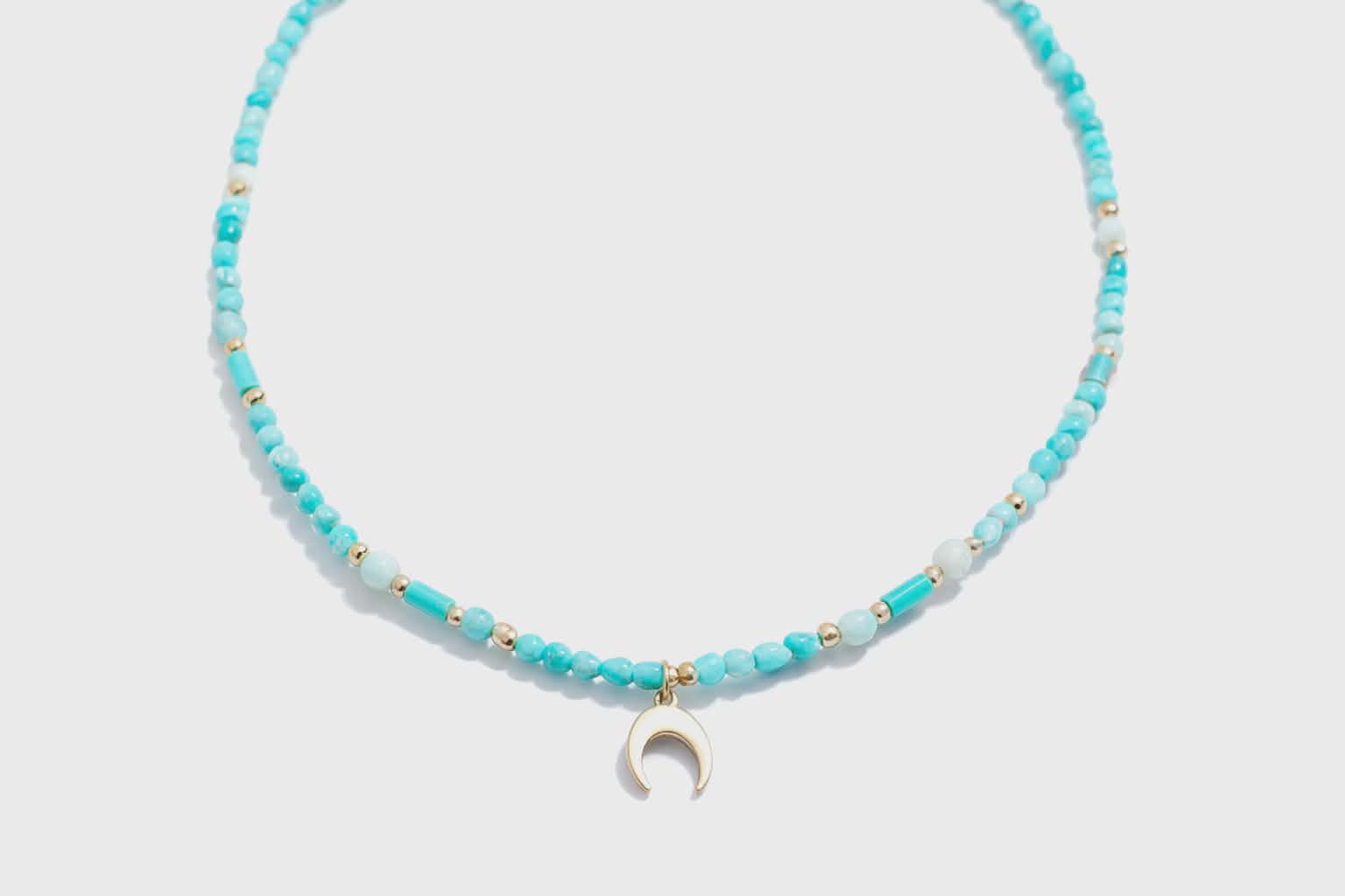 Collier amazonite sur fond clair avec pendentif lune en croissant, perles bleu lagon et vert d’eau pour communication apaisée et douceur du ressenti