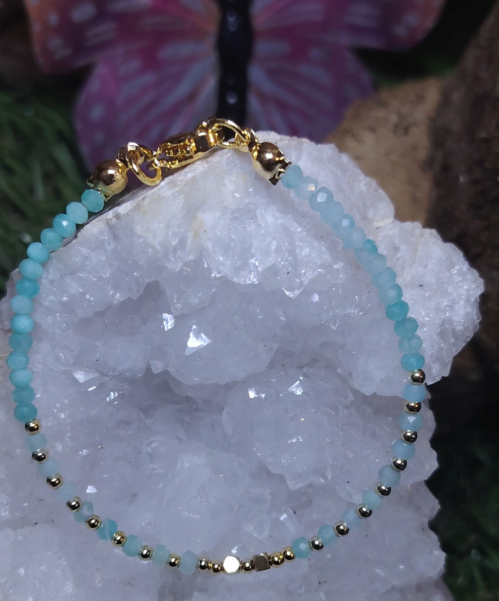 Bracelet amazonite bleu lagon avec intercalaires en cuivre plaqué or, posé sur quartz et pierres naturelles, bijou délicat pour calme intérieur.
