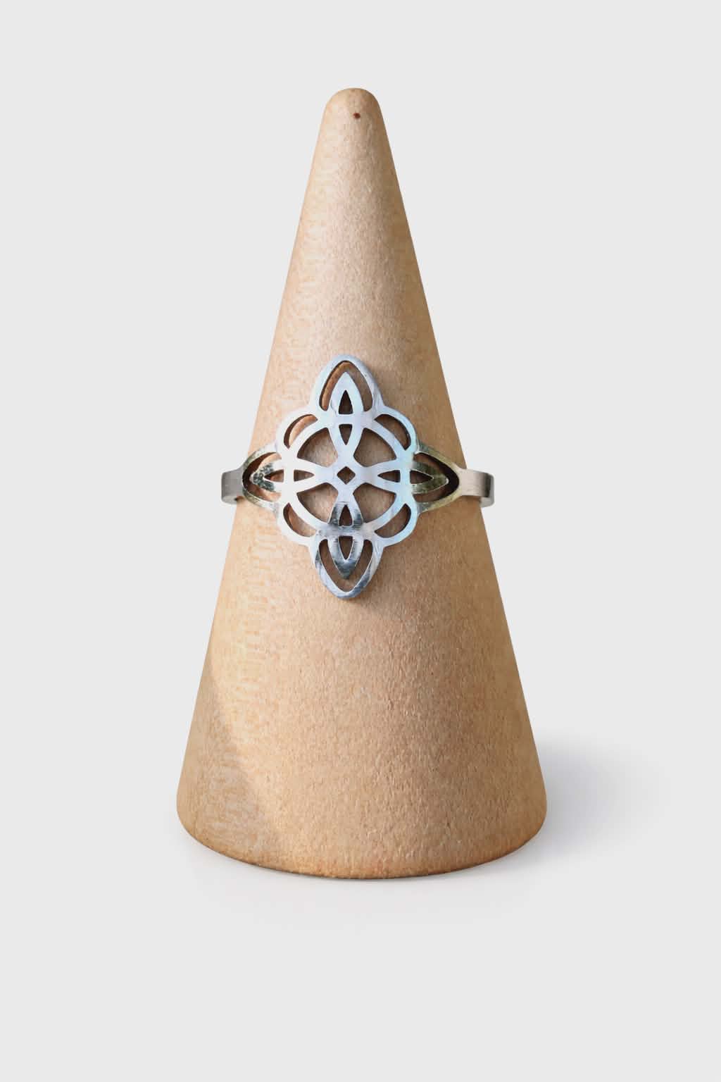 Bague réglable acier inoxydable argenté, nœud de sorcière ajouré, sur cône porte-bague beige, fond blanc; symbole de protection