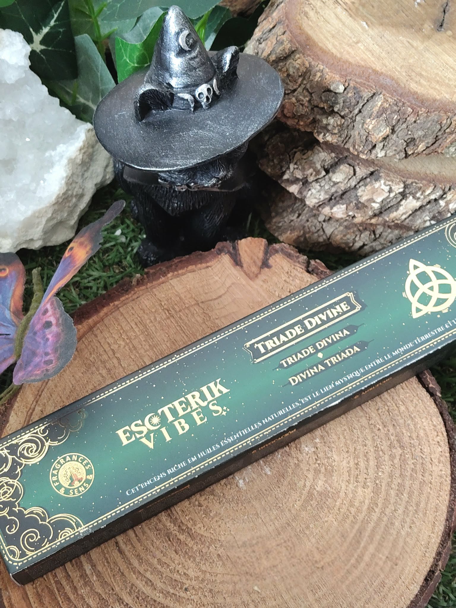 Encens Esoteric Vibes triquetra en scène nature sur rondin et vert profond, avec objet noir et feuillage; favorise recentrage, calme intérieur et harmonie du lieu.