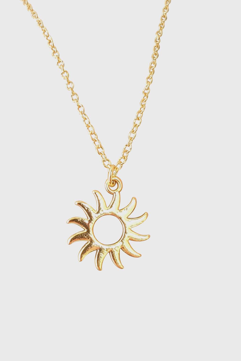 Collier soleil doré en acier inoxydable sur fond blanc, pendentif ajouré sur chaîne fine pour rayonnement, assurance et énergie solaire