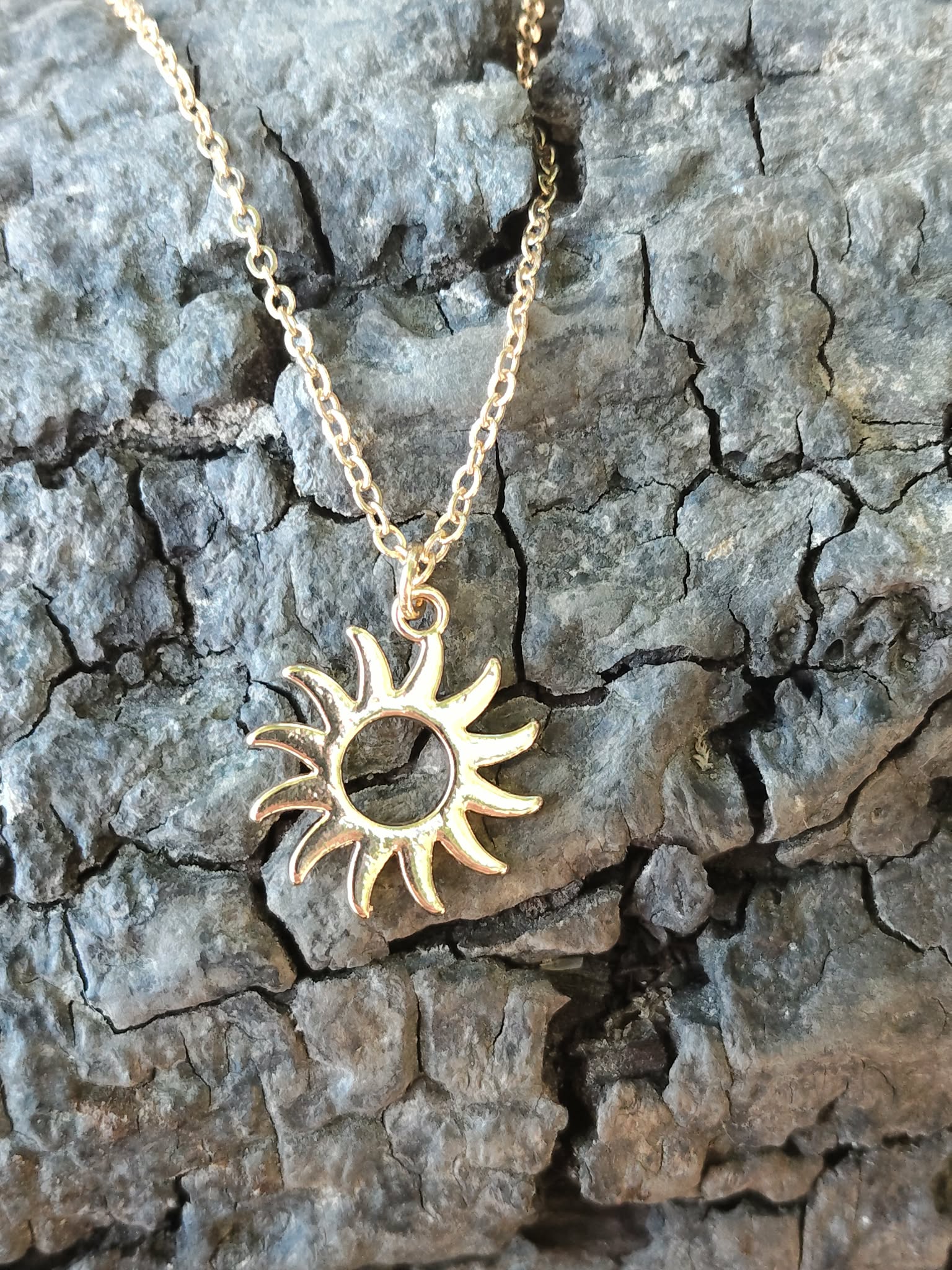 Pendentif soleil doré en acier inoxydable sur écorce en Bretagne, bijou fin au symbole solaire pour élan intérieur et bonne humeur