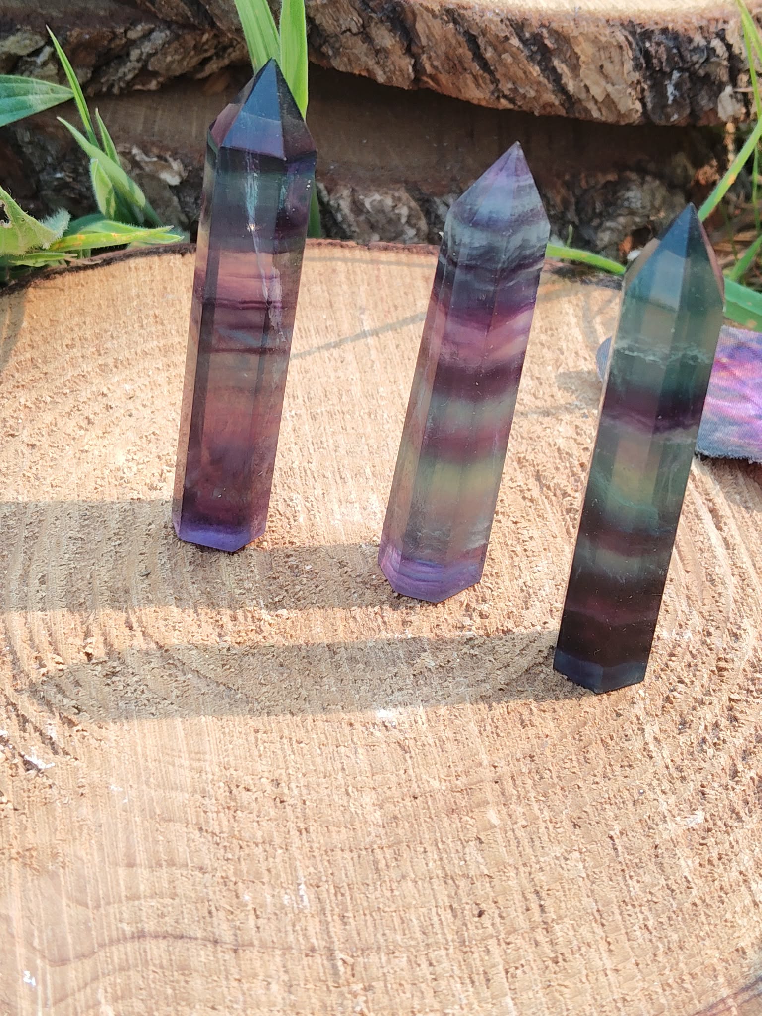 Lot de pointes de fluorite multicolore à bandes vertes, violettes et bleues sur support en bois avec décor végétal, pierres naturelles associées à la cohérence intérieure, à la stabilité et à la clarté d’esprit.