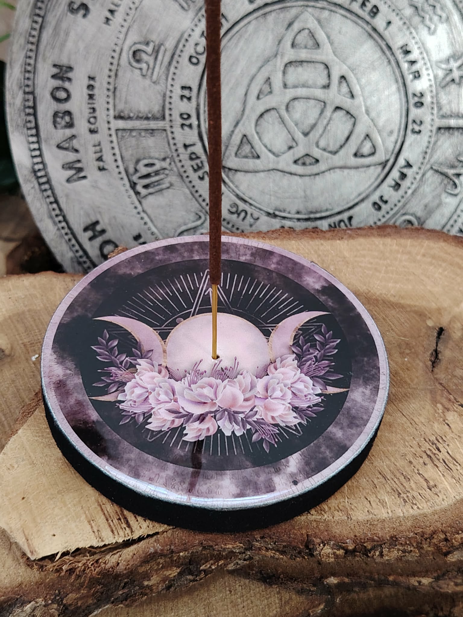Porte-encens rond Triple Lune avec bâton d’encens, posé sur tranche de bois; symbole des cycles lunaires, intuition et protection.