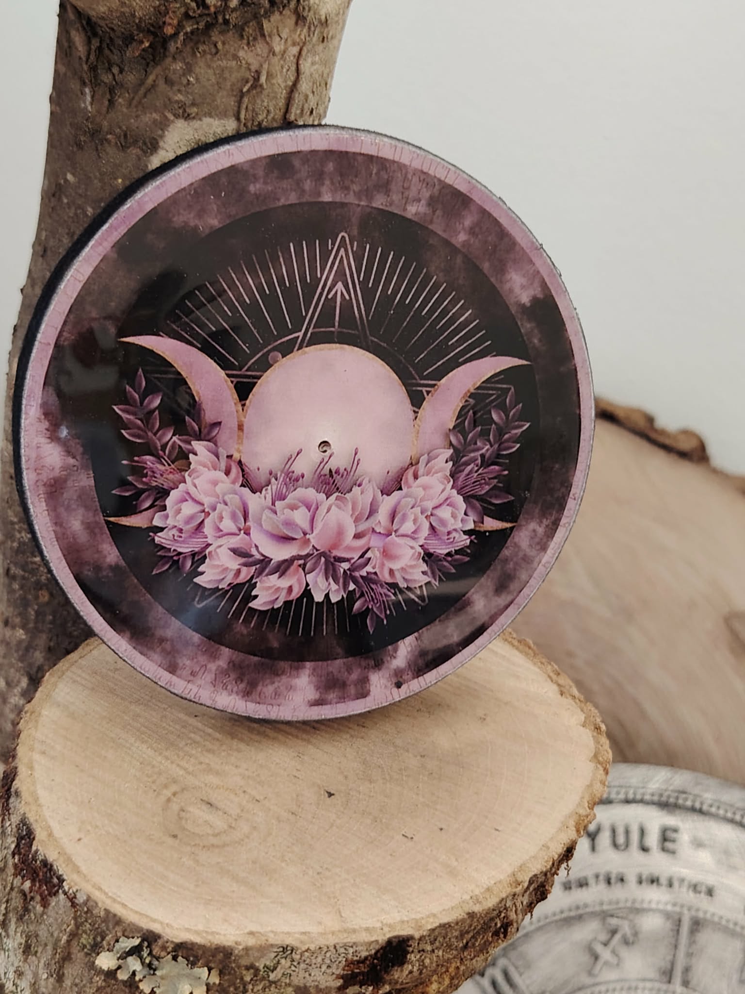Porte-encens rond Triple Lune (lune rose, croissants, fleurs), posé sur une tranche de bois avec décor ésotérique Yule; symbole des cycles, intuition et énergie féminine, pour créer une ambiance douce