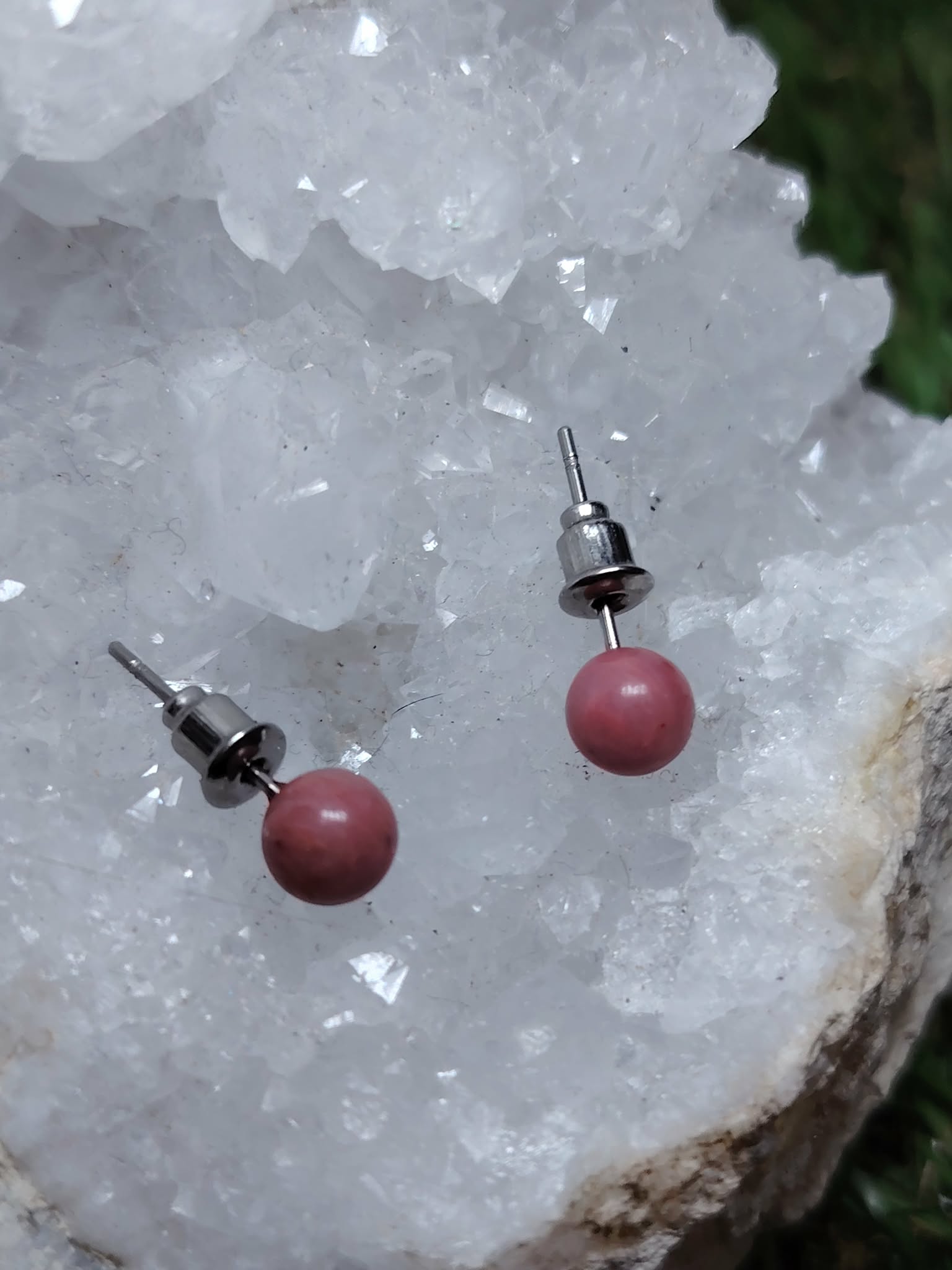 Boucles d’oreilles puces cornaline orange, tiges acier inoxydable, posées sur une géode de quartz; vitalité, motivation, confiance.