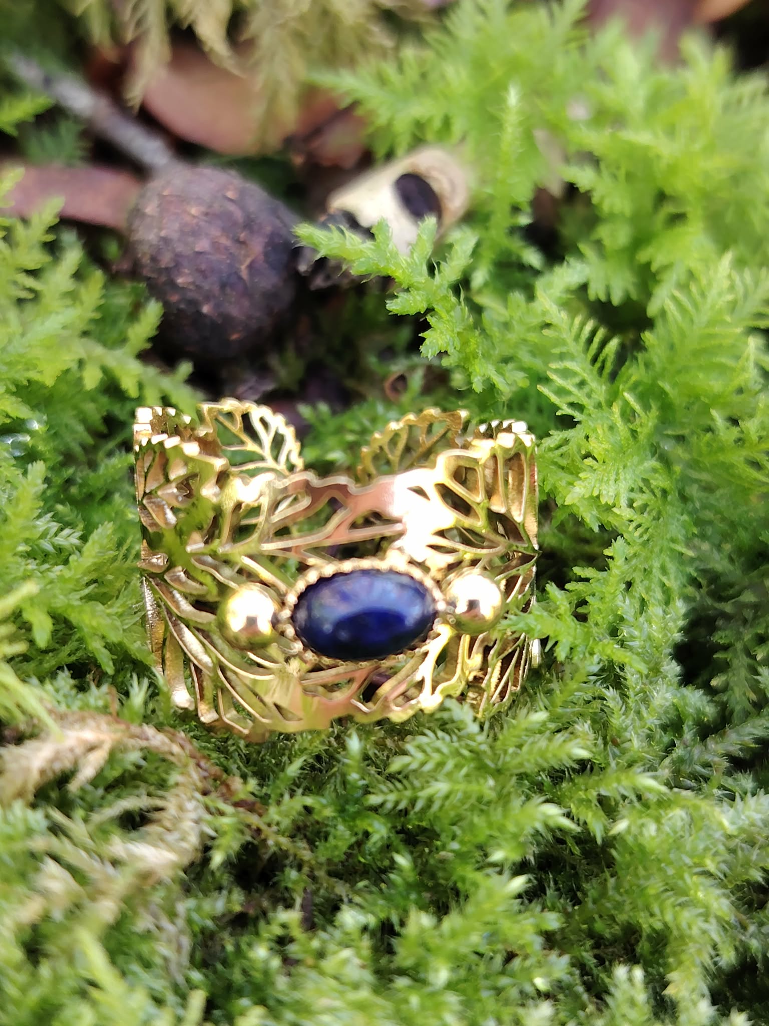 Bague dorée réglable en acier inoxydable, motif feuilles et pierre ovale lapis-lazuli, photo en Bretagne sur mousse.