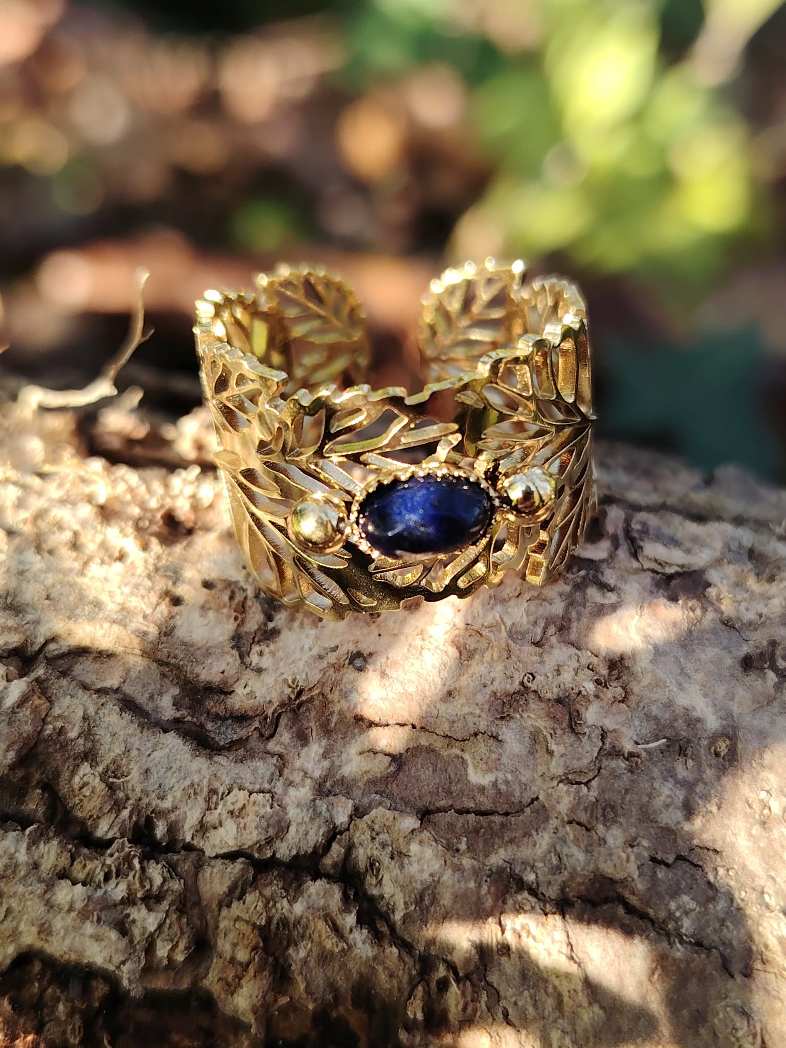 Bague dorée réglable en acier inoxydable, motif feuilles et pierre ovale lapis-lazuli, photo en Bretagne sur écorce.