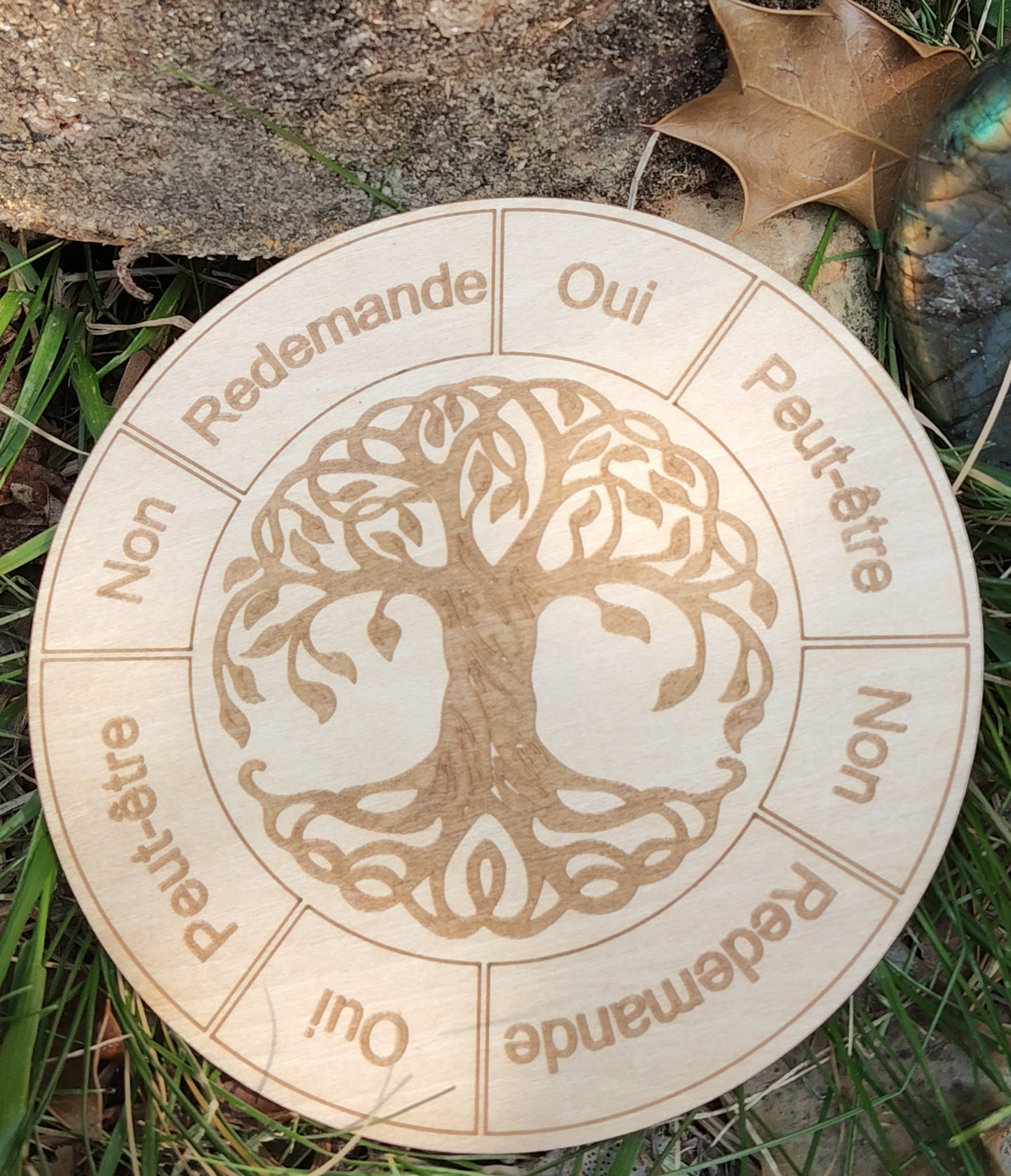Plateau de pendule en bois gravé Arbre de Vie, avec réponses Oui / Non / Peut-être / Redemande, posé sur herbe.
