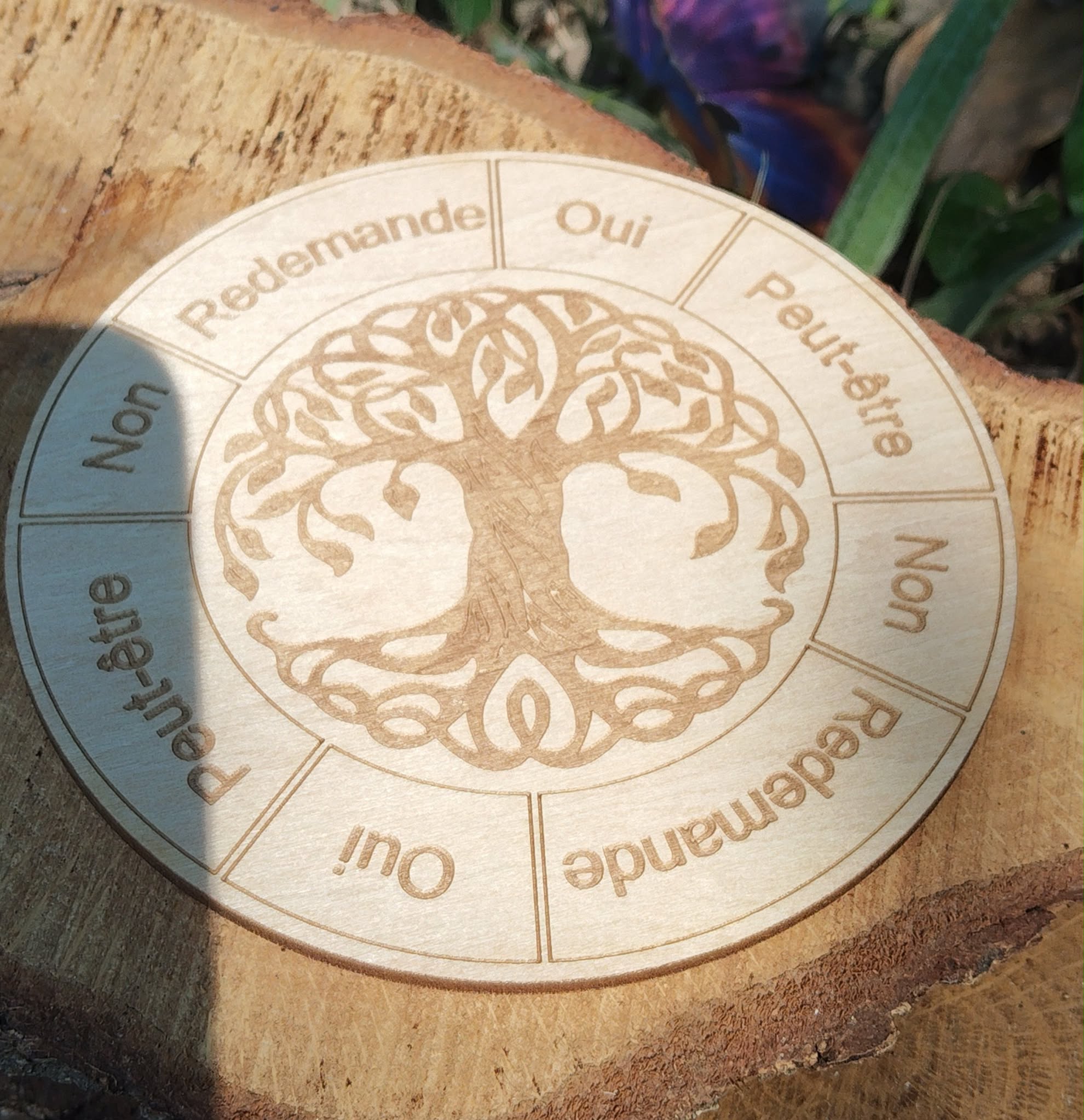 Plateau de pendule en bois gravé Arbre de Vie, posé sur une tranche de bois en extérieur; zones Oui / Non / Peut-être / Redemande.