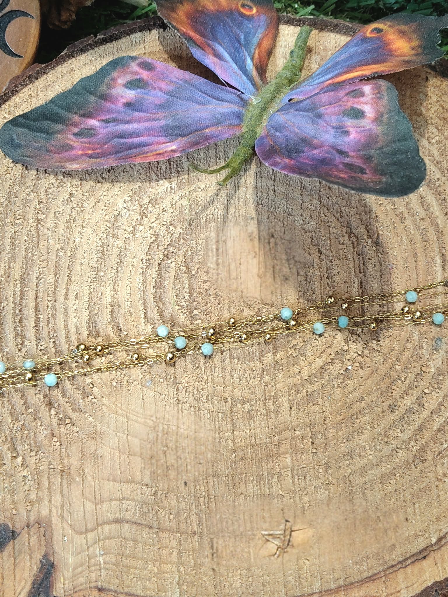 Bracelet multi-rangs en amazonite facettée sur tranche de bois avec papillon violet, fines chaînes dorées et style bohème