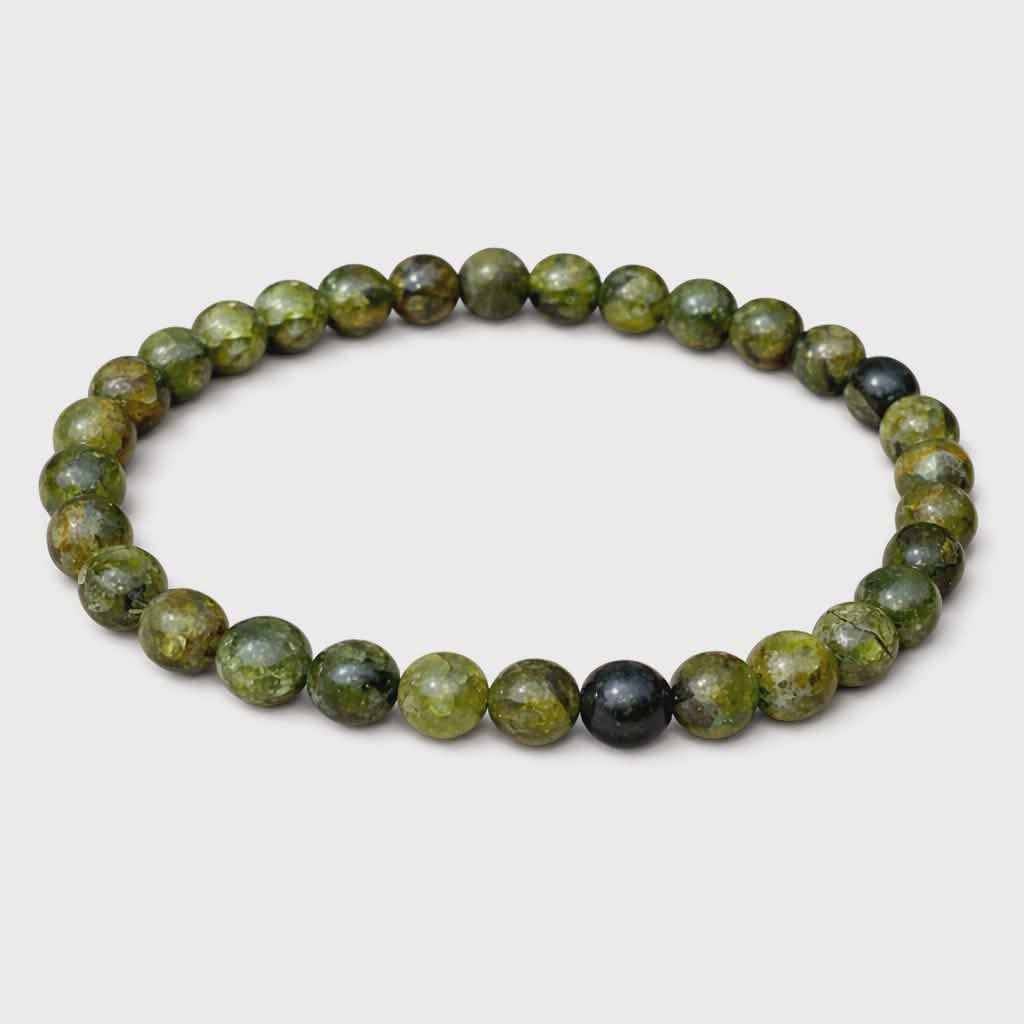 Bracelet péridot sur fond blanc, perles vert marbré et noires sur élastique pour optimisme, clarté émotionnelle et confiance tranquille