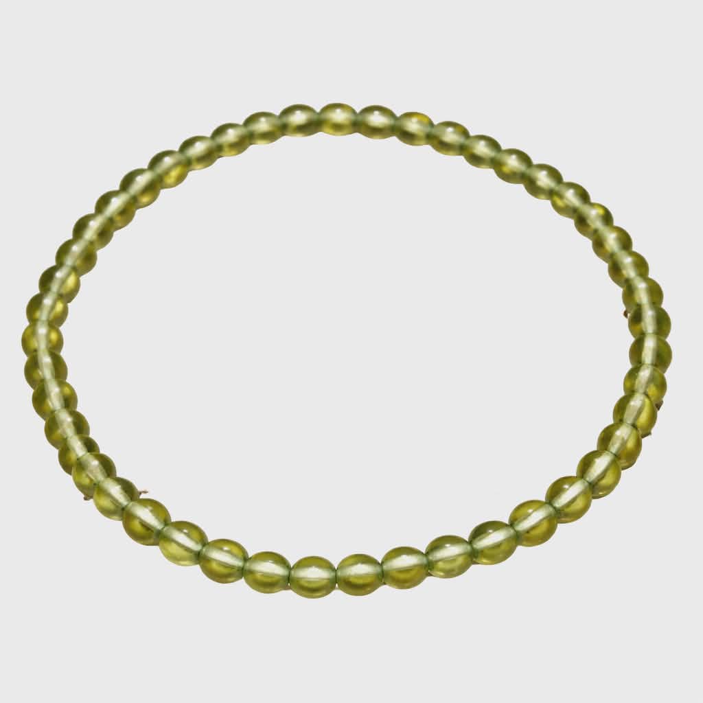 Bracelet en péridot (perles 4 mm vert olive translucide), monté sur fil élastique, présenté seul sur fond blanc en forme ovale ; rendu lumineux et naturel, évoque fraîcheur, vitalité et énergie positive.