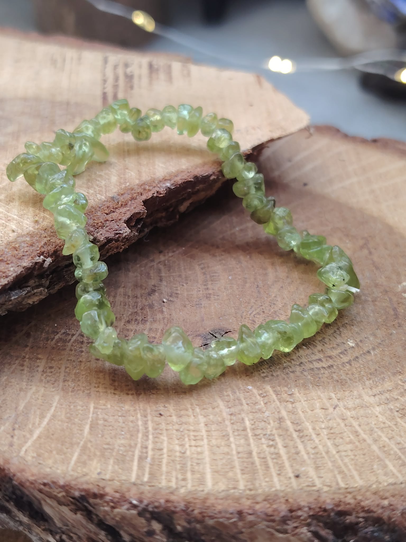 Bracelet péridot baroque présenté dans la main en gros plan, chips vert olive translucides pour énergie de renouveau et sensation de légèreté