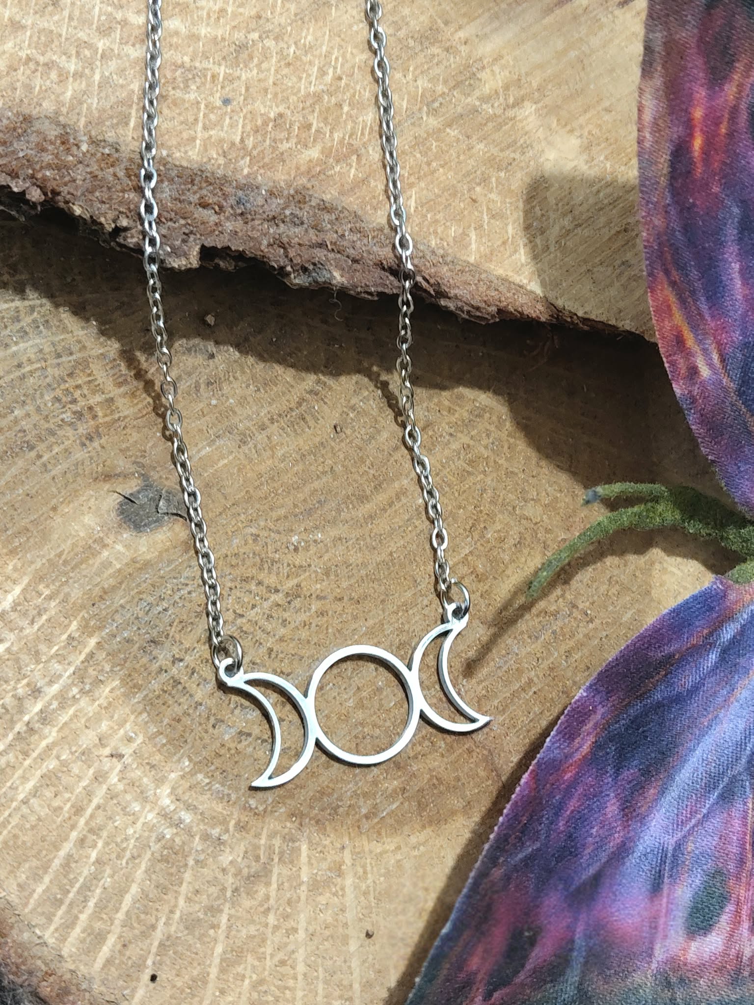 Collier triple lune argenté posé sur une tranche de bois, pendentif lunaire en acier inoxydable au style ésotérique