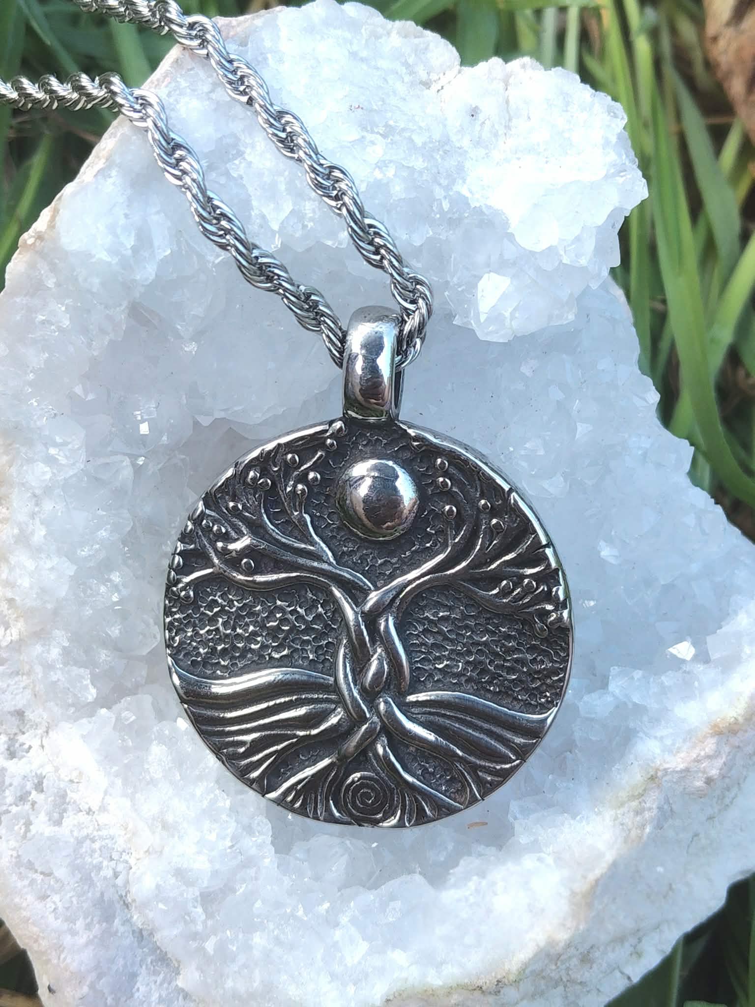 Pendentif Yggdrasil sur fond nature avec géode blanche et touches de vert, symbole de continuité, de vitalité et de recentrage
