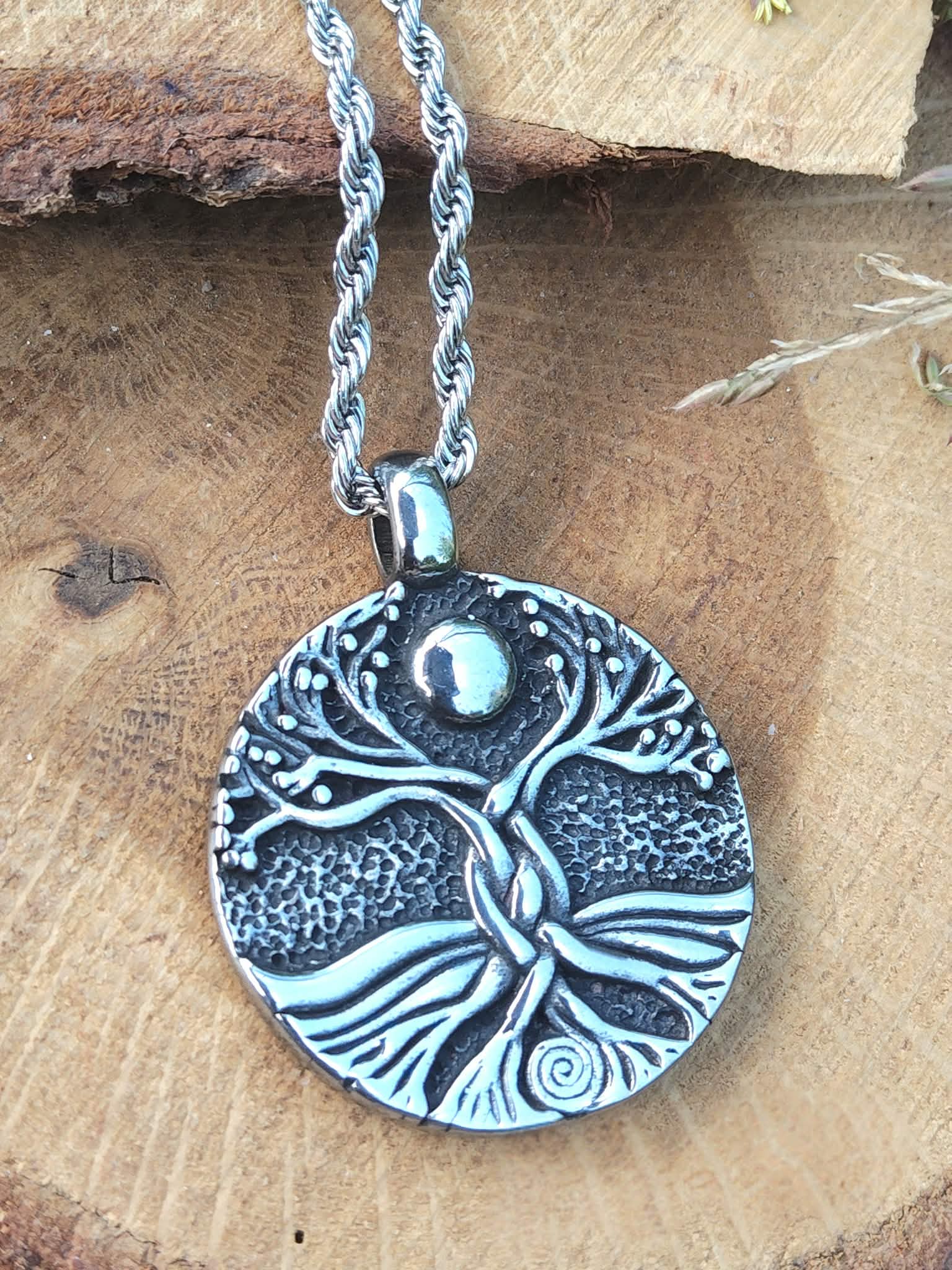Collier arbre de vie rond sur bois clair avec touche de verdure, stabilité émotionnelle, recentrage et présence solide