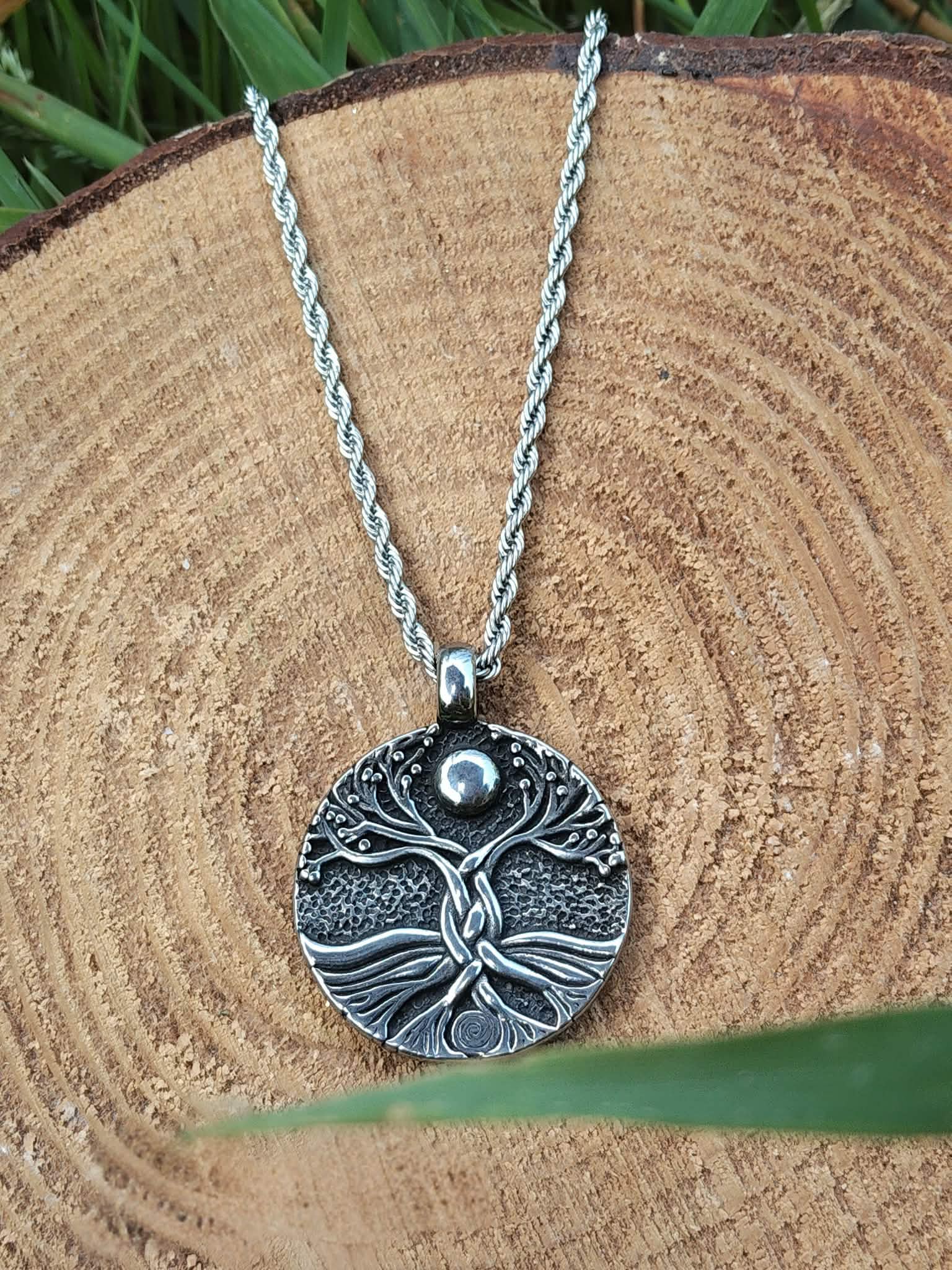 Collier Yggdrasil argenté sur rondin de bois en décor forestier, énergie de renouveau et cheminement intérieur