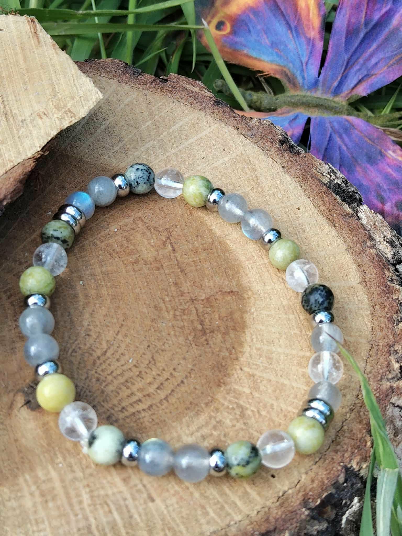 Bracelet vampire énergétique sur rondin de bois avec carte et feuillage, pierres naturelles pour se préserver des ambiances lourdes et retrouver un axe stable