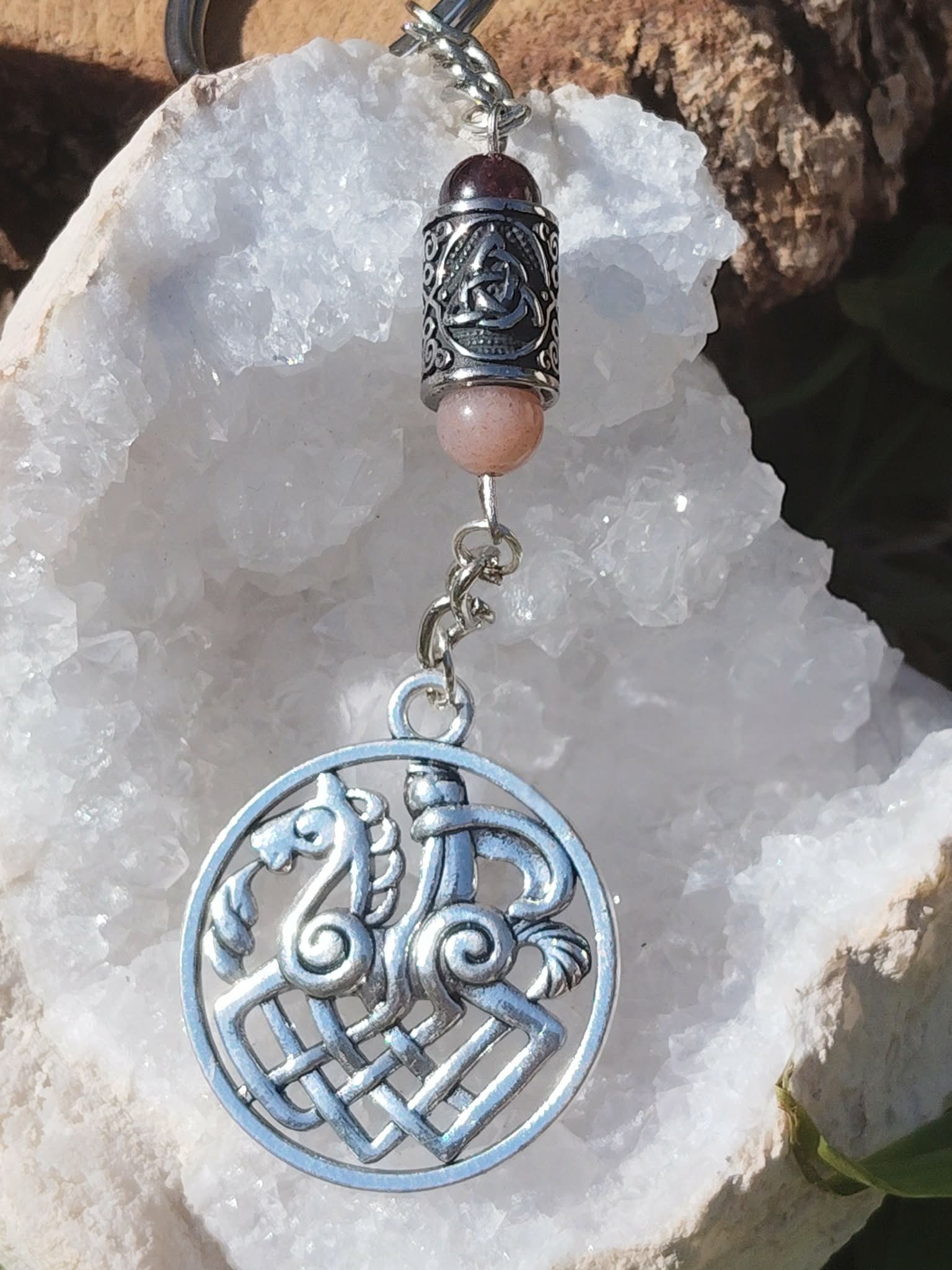 Bijou de sac Odin Sleipnir avec pierre de soleil   grenat, photo sur géode de quartz blanche. Création Magic Gaïa : énergie, confiance, stabilité.