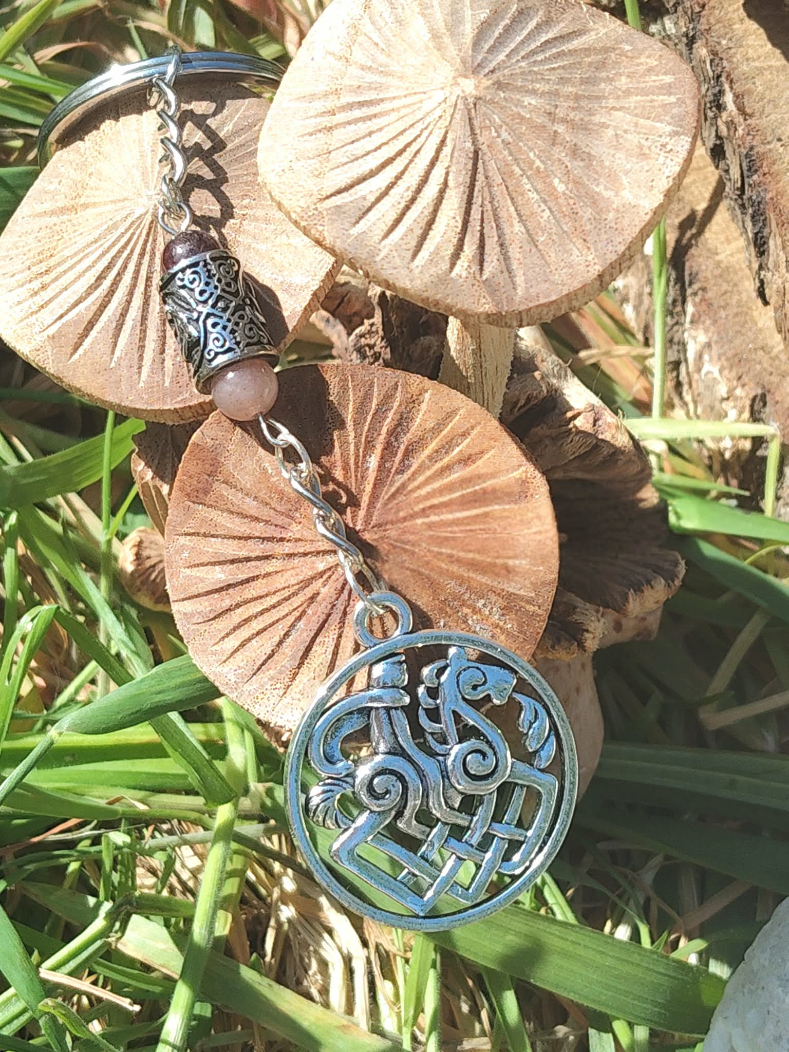 Bijou de sac Odin Sleipnir avec pierre de soleil et grenat, décor champignons et végétation. Création Magic Gaïa : motivation, force, stabilité.