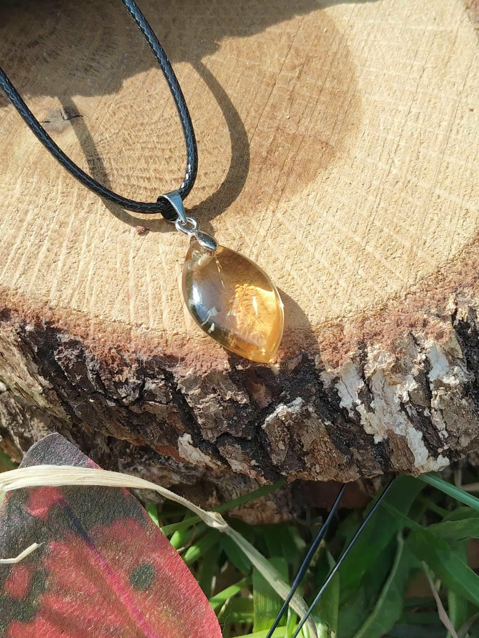 Pendentif citrine sur cordon noir, posé sur champignon et mousse avec carte rouge en bas, pierre naturelle liée à la lucidité, à l’énergie chaleureuse et à l’élan personnel.